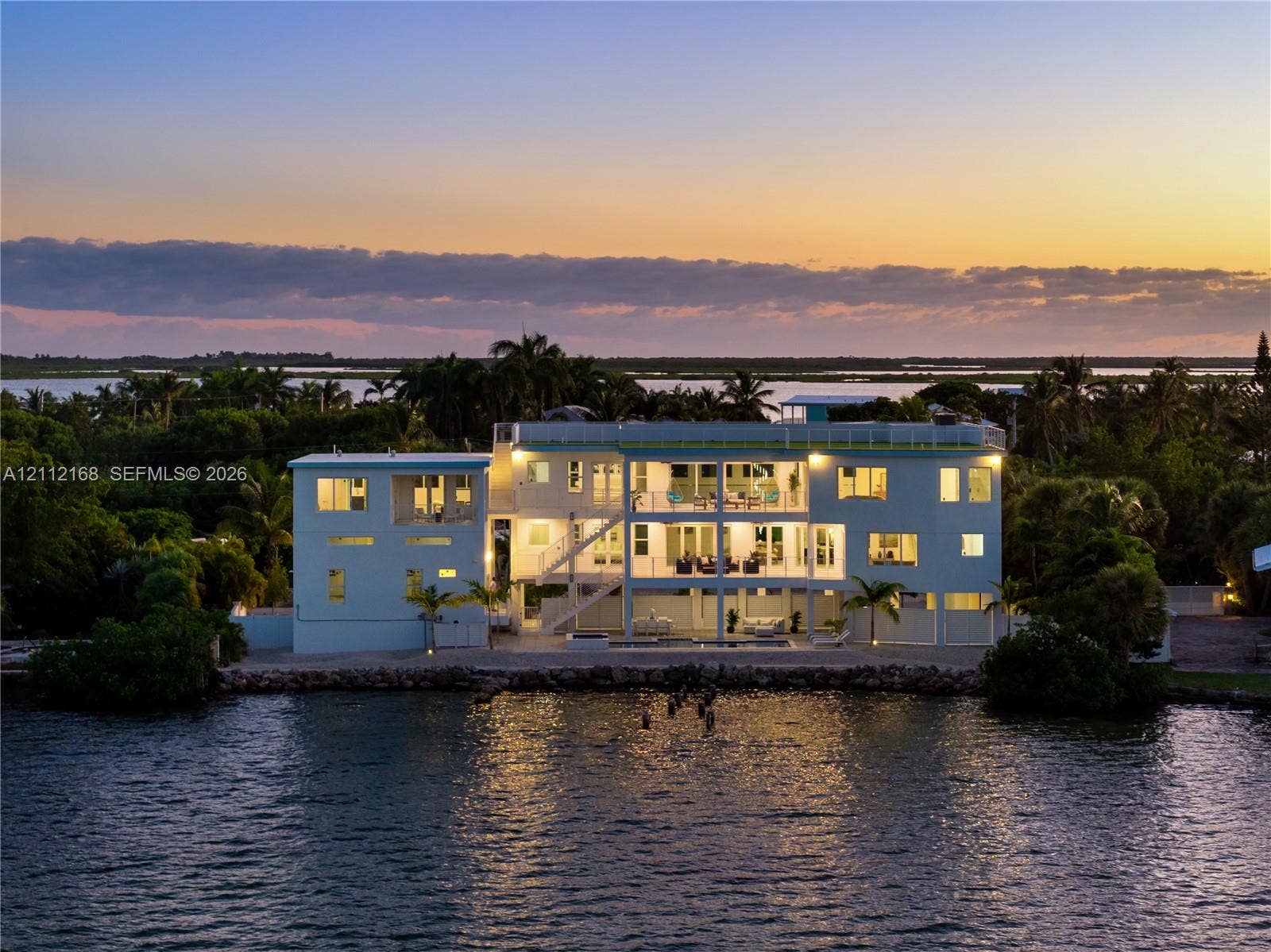 1041 E Buttonwood Drive, Sugarloaf Key, FL 33042 Waterfront residence featuring multi-level balconies, expansive glass windows, a flat roofline, and a private dock