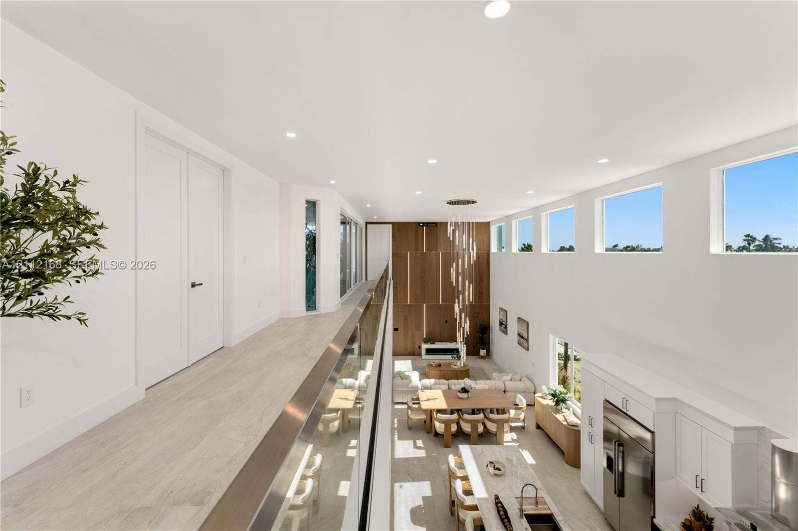 1041 E Buttonwood Drive, Sugarloaf Key, FL 33042 Elevated walkway featuring a sleek glass railing, wood-finish flooring, soaring ceilings, clerestory windows, and a multi-tiered modern chandelier