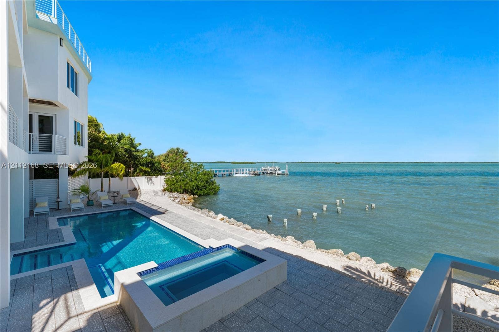 1041 E Buttonwood Drive, Sugarloaf Key, FL 33042 Waterfront property featuring an in-ground swimming pool, integrated spa, paved stone deck, and a private boat dock