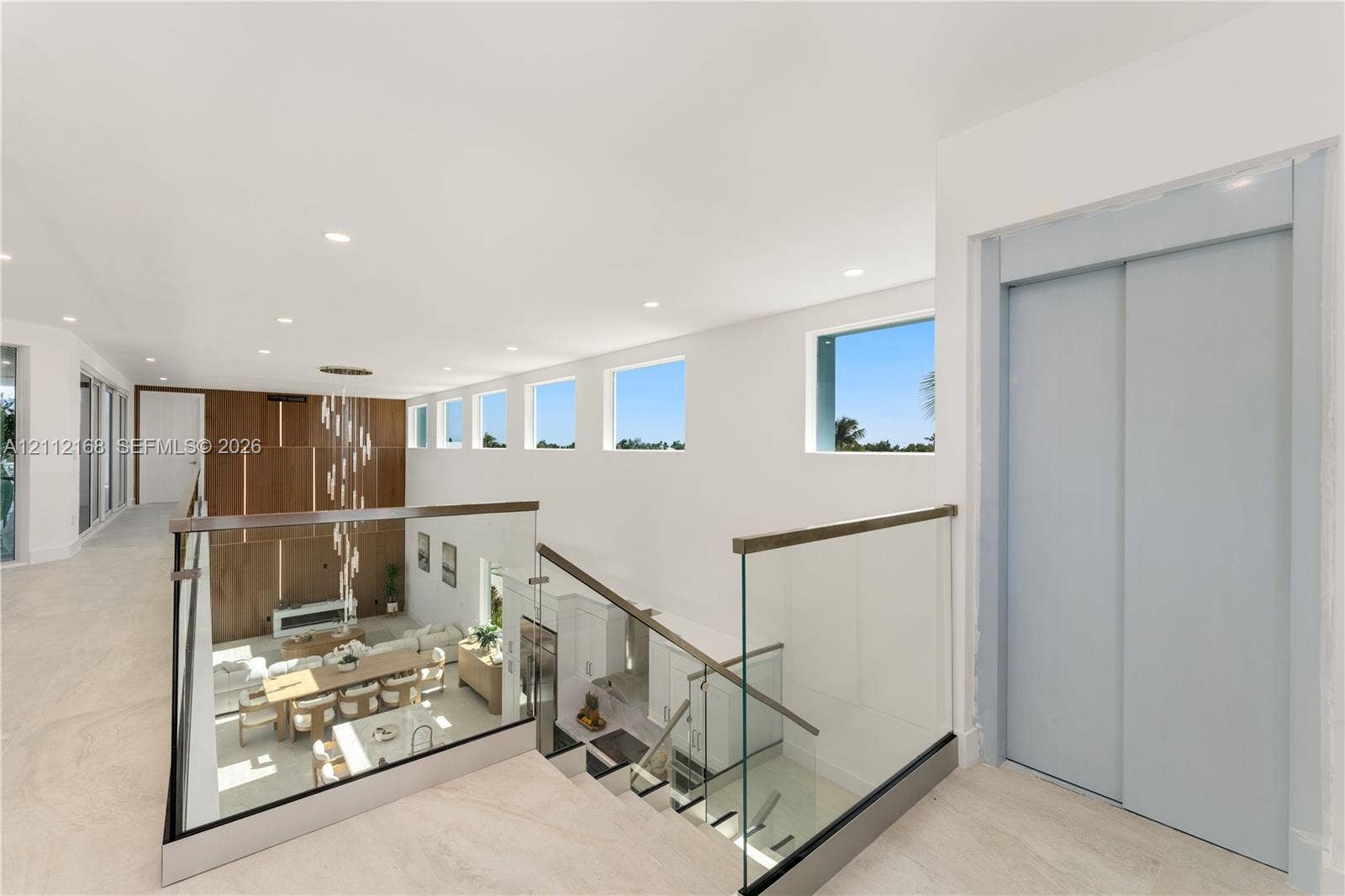 1041 E Buttonwood Drive, Sugarloaf Key, FL 33042 Open landing featuring large-format tile flooring, a glass-panel railing with a wood-finish handrail, a private elevator, recessed ceiling lighting, and a series of high-placement fixed windows