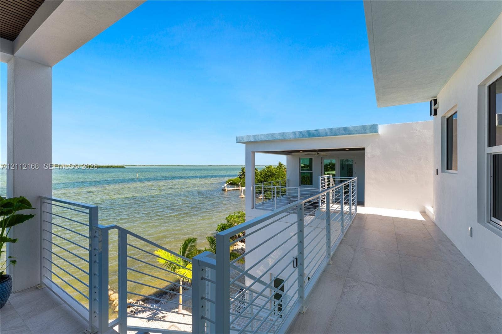 1041 E Buttonwood Drive, Sugarloaf Key, FL 33042 Covered waterfront balcony featuring large-format tile flooring, white metal cable railing, and a tongue-and-groove wood-finish ceiling