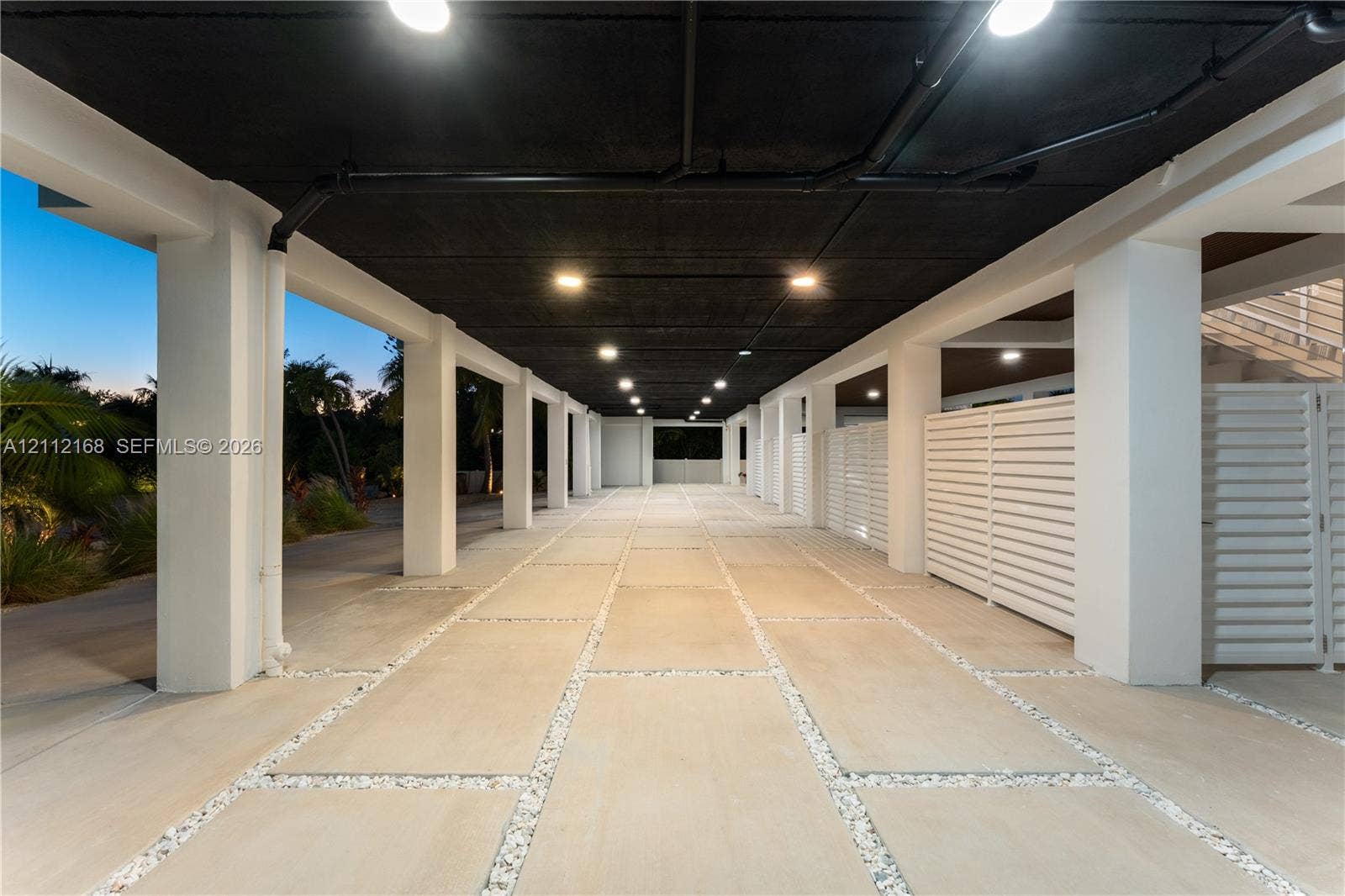 1041 E Buttonwood Drive, Sugarloaf Key, FL 33042 Covered parking area featuring concrete pavers, white lattice privacy screens, structural support columns, and recessed ceiling lighting