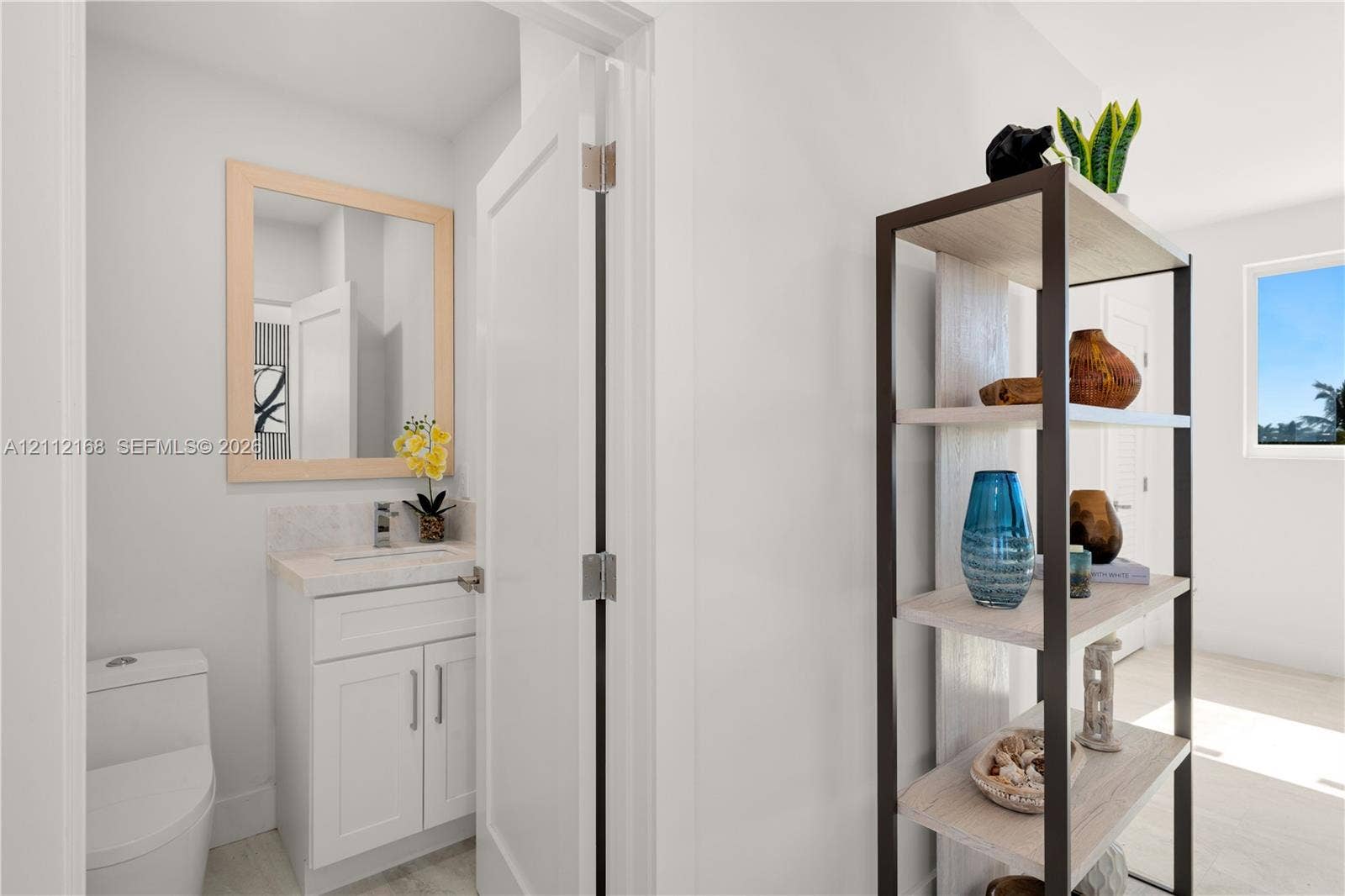 1041 E Buttonwood Drive, Sugarloaf Key, FL 33042 White cabinetry with stone-surfaced countertop, integrated under-mount sink, polished chrome faucet, and rectangular mirror with light wood-finish frame