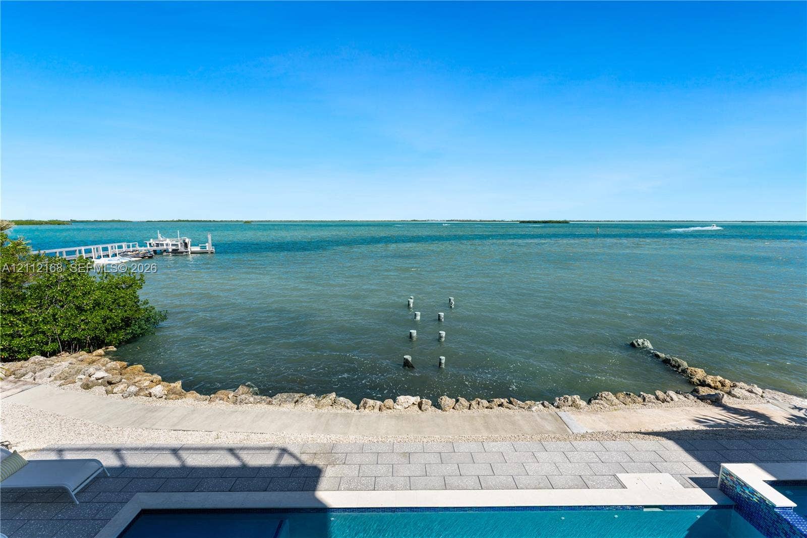 1041 E Buttonwood Drive, Sugarloaf Key, FL 33042 Waterfront property featuring a private swimming pool, stone-paver patio, rock-lined seawall, and a private dock