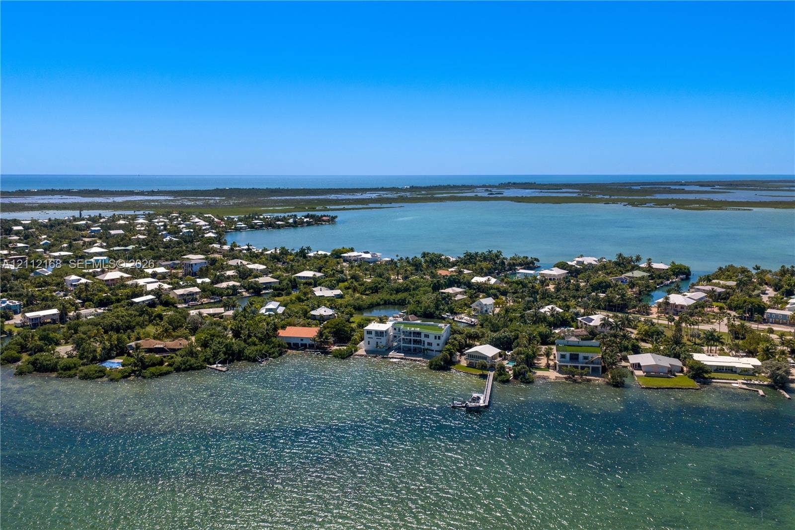 1041 E Buttonwood Drive, Sugarloaf Key, FL 33042 Aerial perspective of coastal property featuring direct water frontage, a private deep-water dock, and tropical vegetation within a waterfront setting