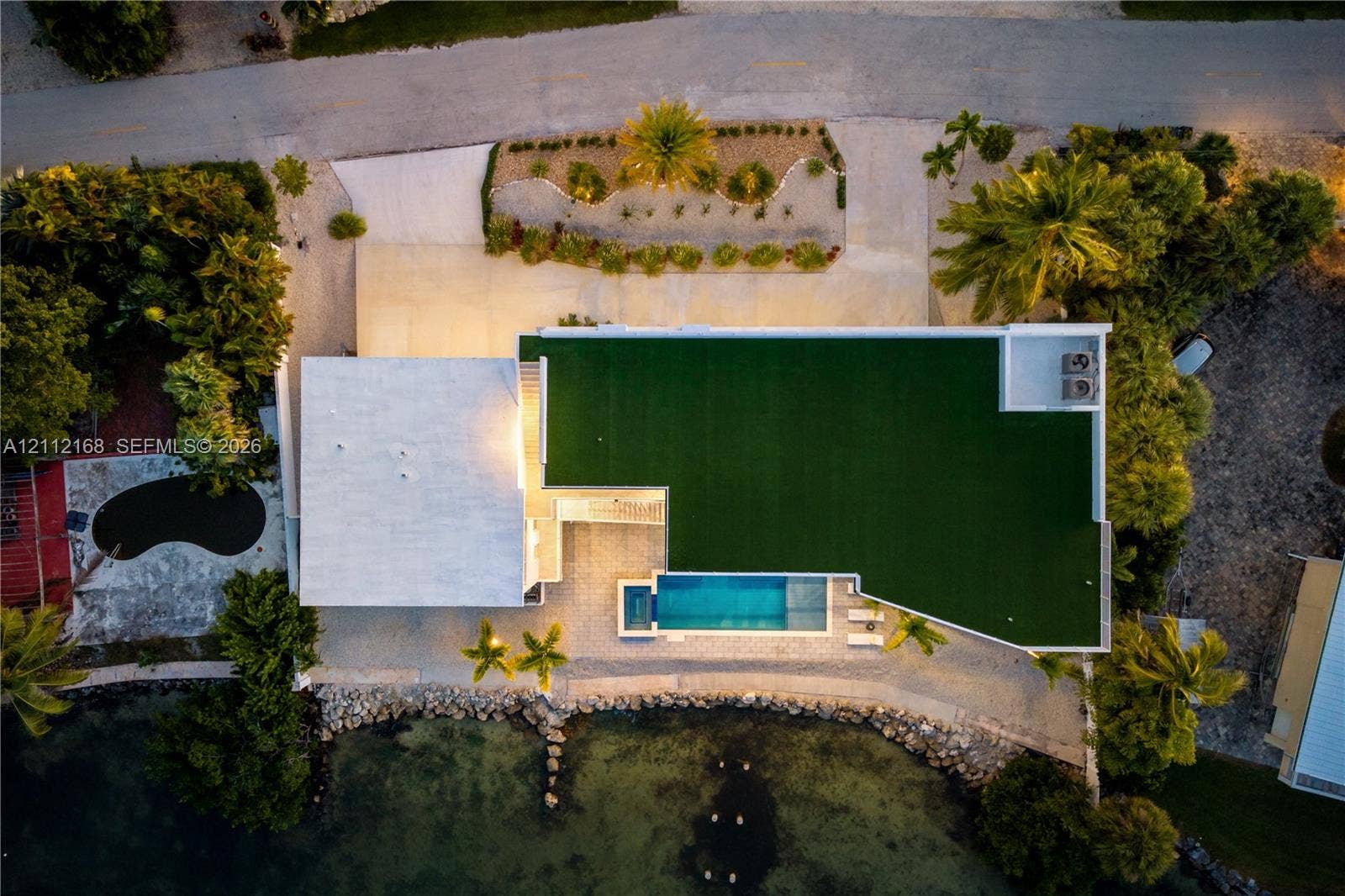 1041 E Buttonwood Drive, Sugarloaf Key, FL 33042 Aerial perspective featuring a waterfront property with an in-ground pool, concrete paved driveway, and established landscaping