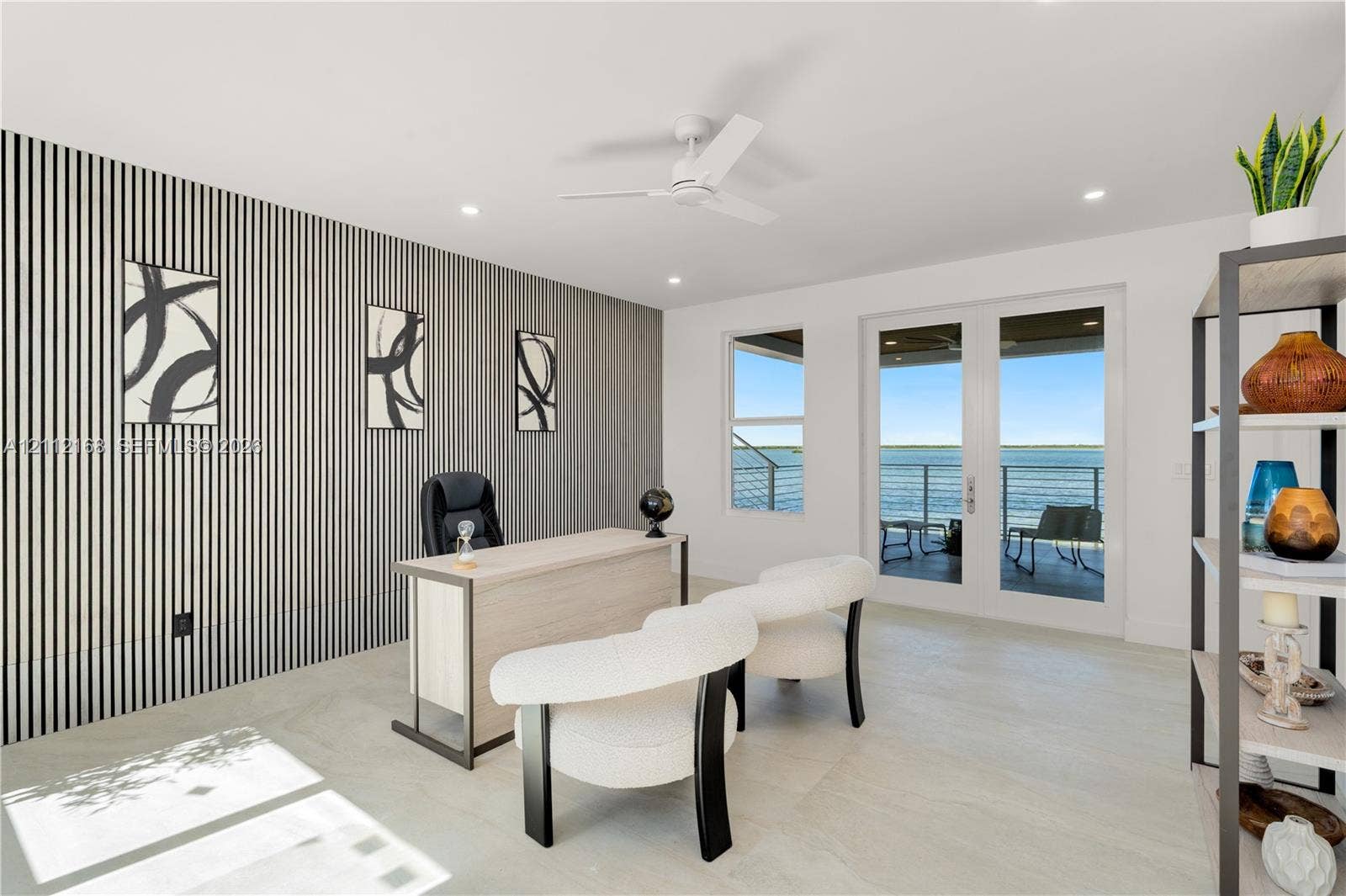 1041 E Buttonwood Drive, Sugarloaf Key, FL 33042 Accent wall with vertical paneling, light-toned flooring, white ceiling fan, and double glass doors providing external water-front access