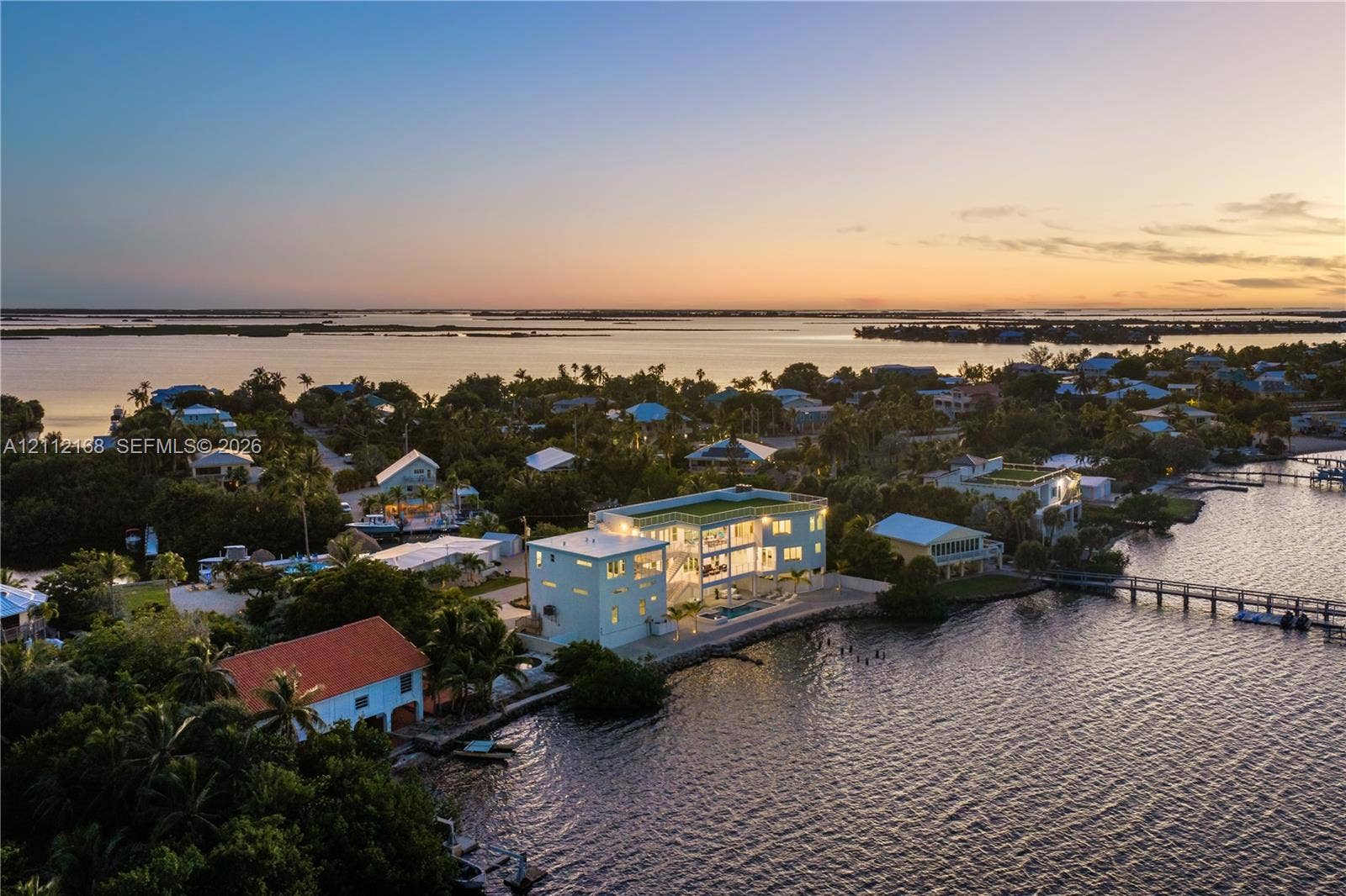 1041 E Buttonwood Drive, Sugarloaf Key, FL 33042 Contemporary multi-story residence featuring expansive floor-to-ceiling glass walls, a private swimming pool, and direct waterfront access