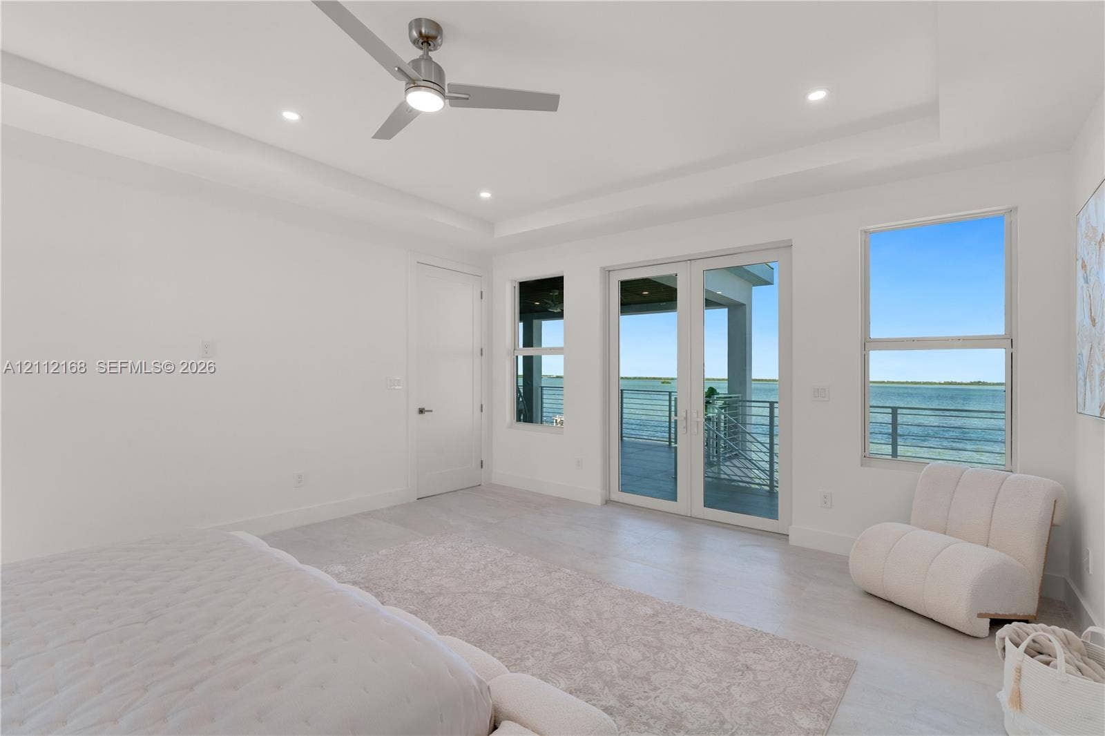 1041 E Buttonwood Drive, Sugarloaf Key, FL 33042 Tray ceiling with brushed nickel ceiling fan, wood-finish flooring, double-glass French doors, and waterfront exterior balcony