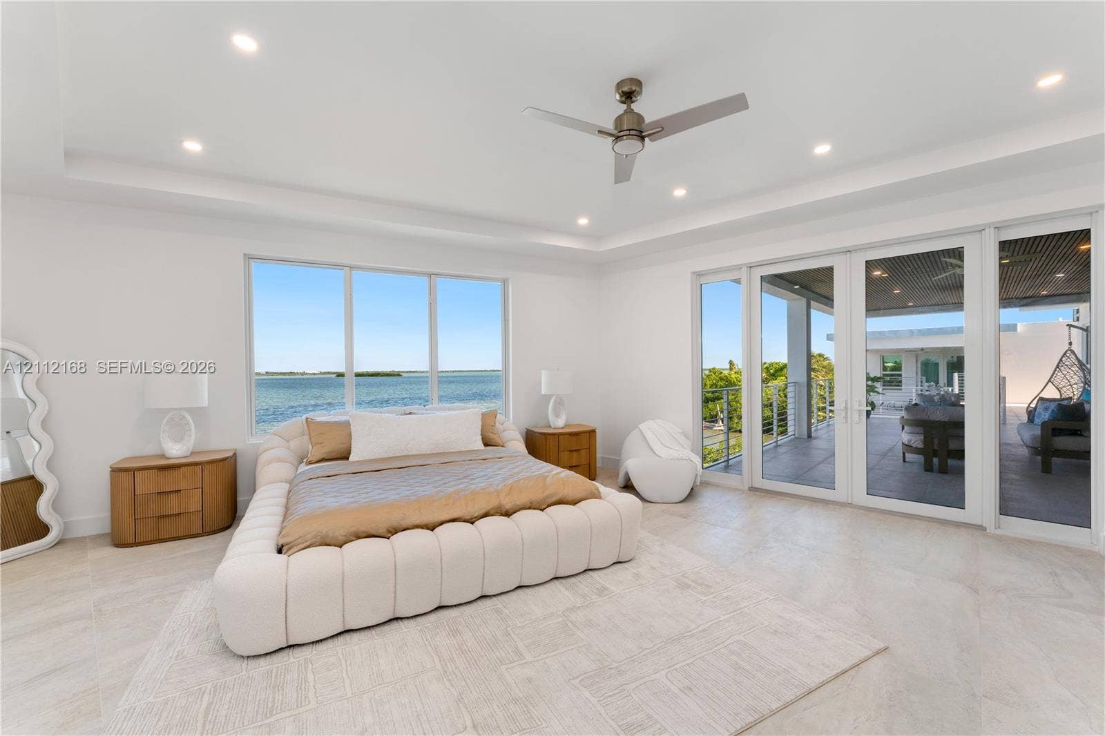 1041 E Buttonwood Drive, Sugarloaf Key, FL 33042 Tray ceiling with recessed lighting, ceiling fan, large windows, and floor-to-ceiling glass panel doors opening to a covered terrace
