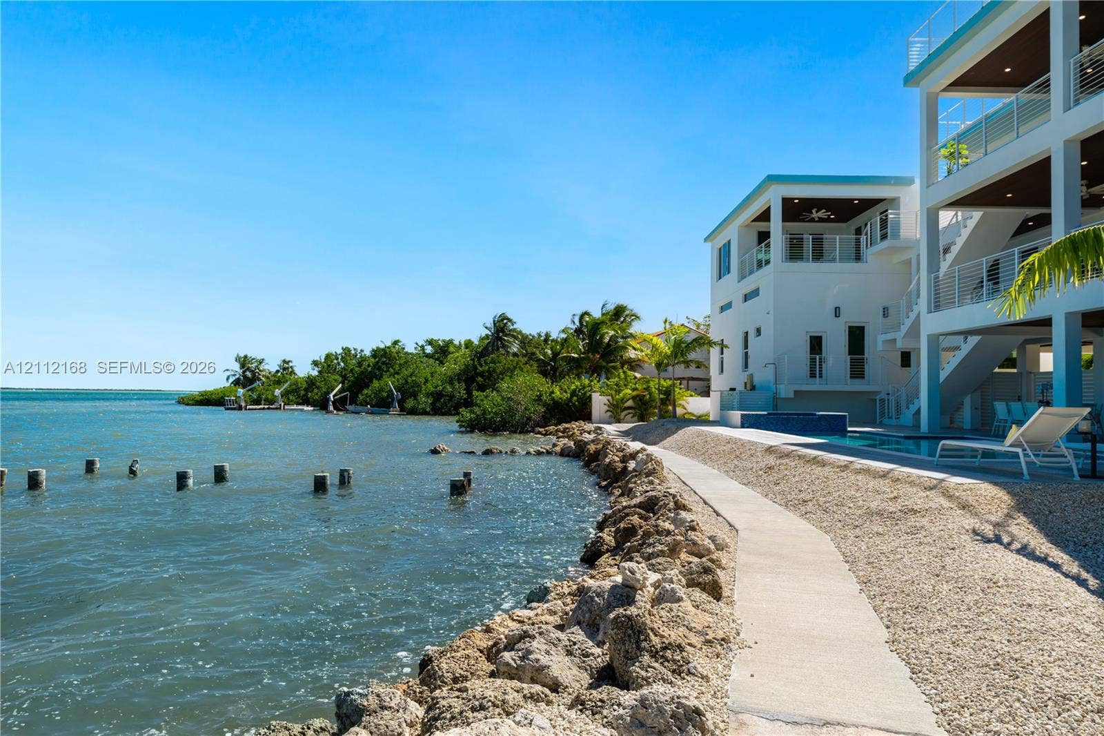 1041 E Buttonwood Drive, Sugarloaf Key, FL 33042 Multi-level coastal residence featuring deep-water access, a private swimming pool, concrete bulkhead, and tiered covered balconies