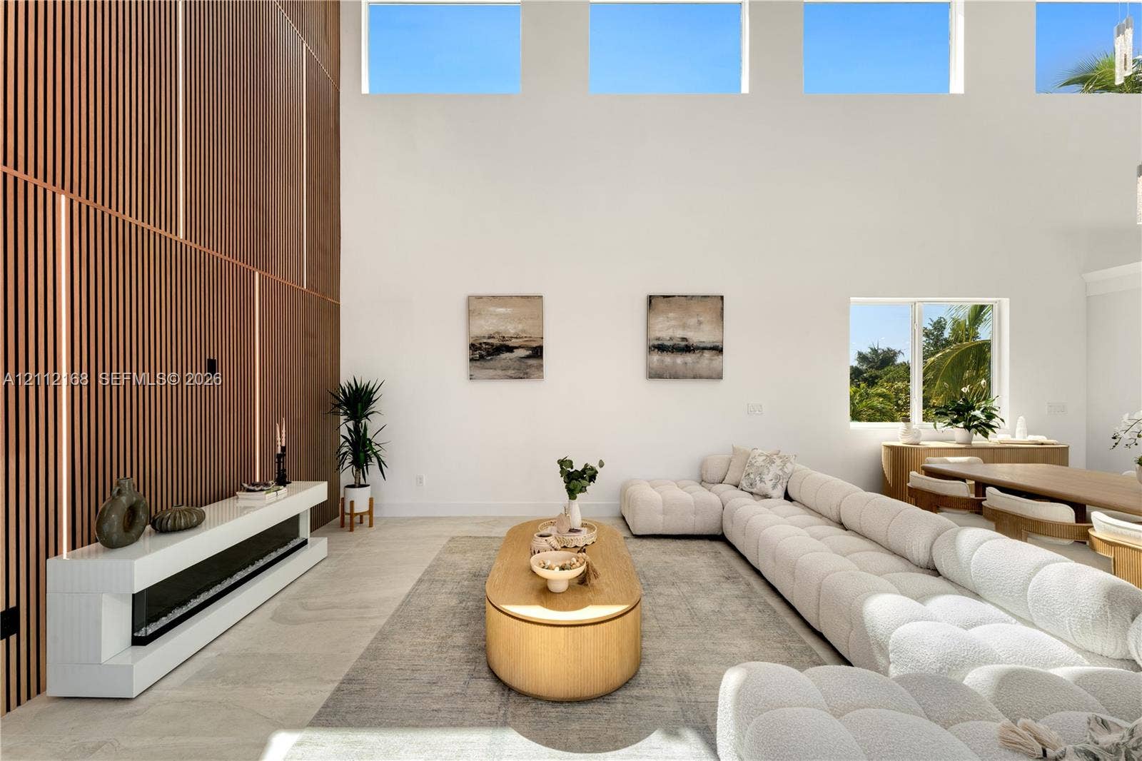 1041 E Buttonwood Drive, Sugarloaf Key, FL 33042 Double-height ceilings with transom windows, full-height vertical wood-slat feature wall, integrated linear fireplace with white floating hearth, and large-format tile flooring