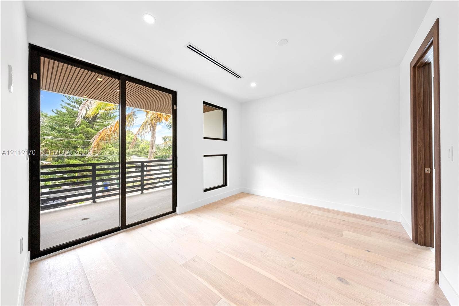 Light-filled room featuring wood-finish flooring, recessed lighting, and expansive glass sliding doors