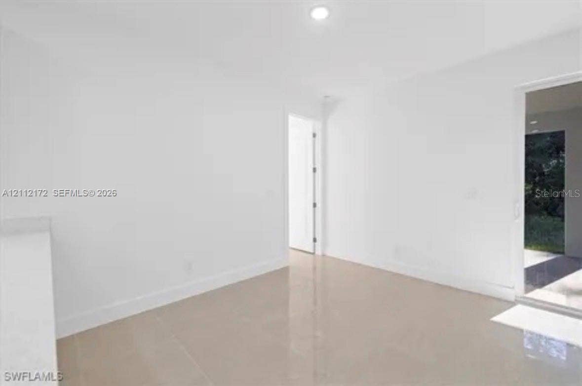 Neutral interior featuring light-toned tile flooring, recessed ceiling lighting, and glass sliding doors