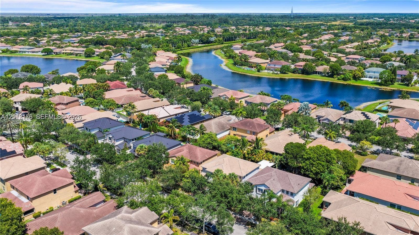19143 Crystal Street, Weston, FL 33332 Aerial perspective of a residential neighborhood featuring multi-phase housing, winding waterways, mature landscaping, and solar panel installations