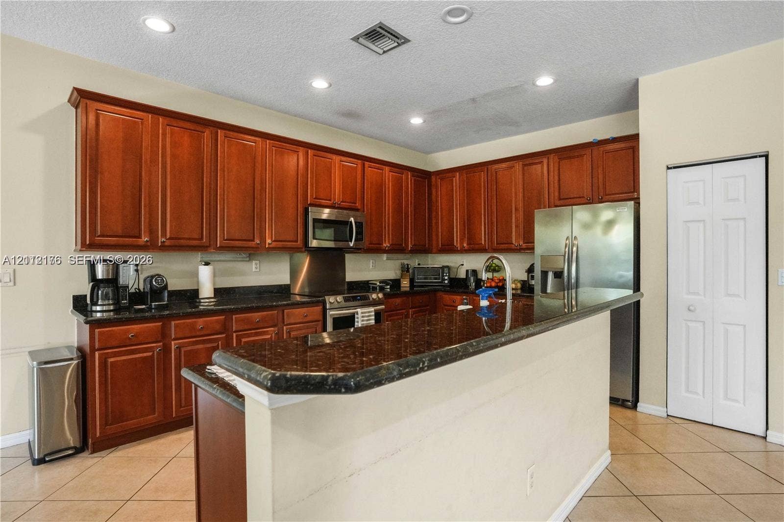 19143 Crystal Street, Weston, FL 33332 Kitchen featuring stained wood cabinetry, stone-surface countertops, breakfast bar, recessed lighting, and stainless steel appliances