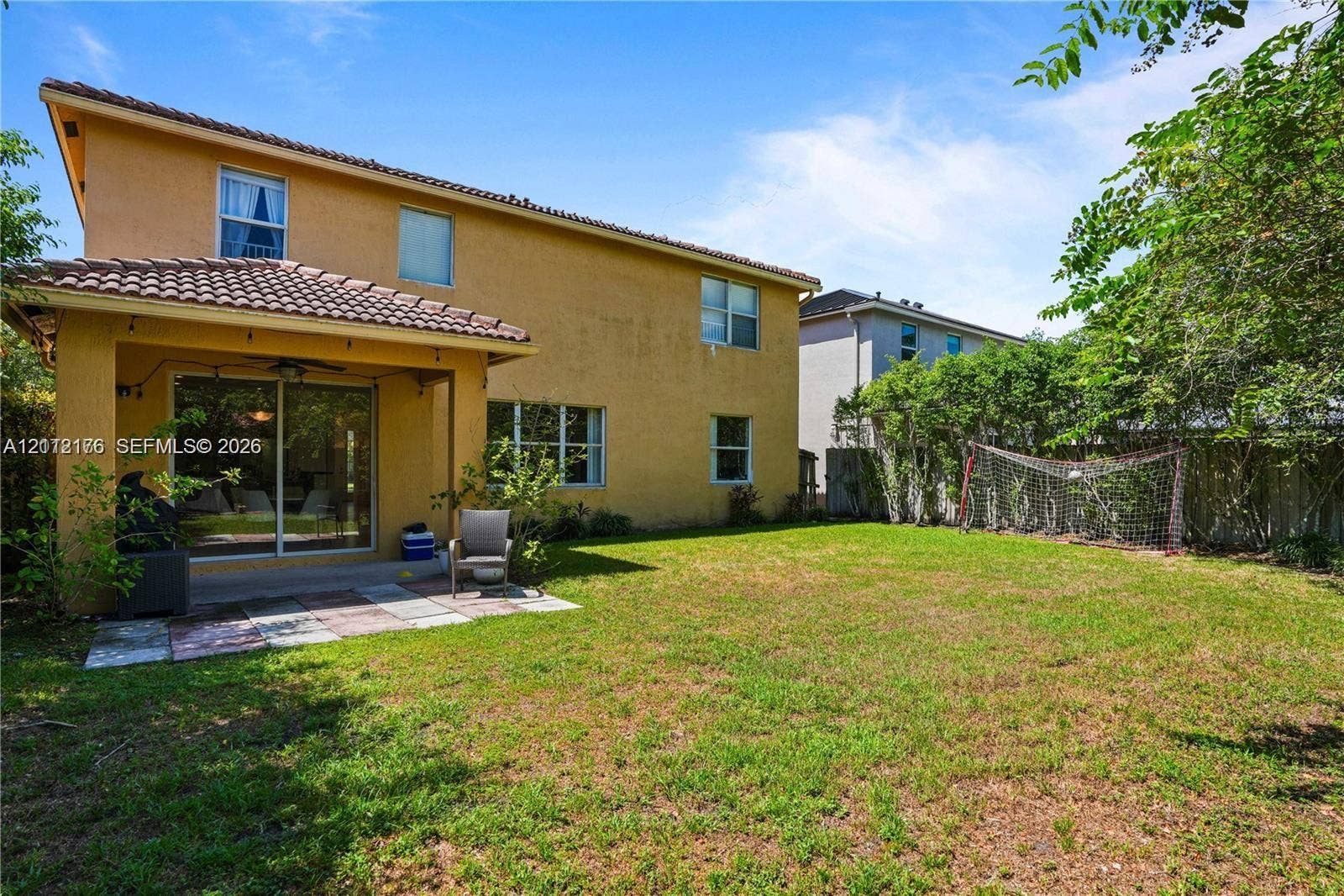 19143 Crystal Street, Weston, FL 33332 Stucco exterior with a covered patio, tile roof, and expansive backyard featuring mature perimeter landscaping