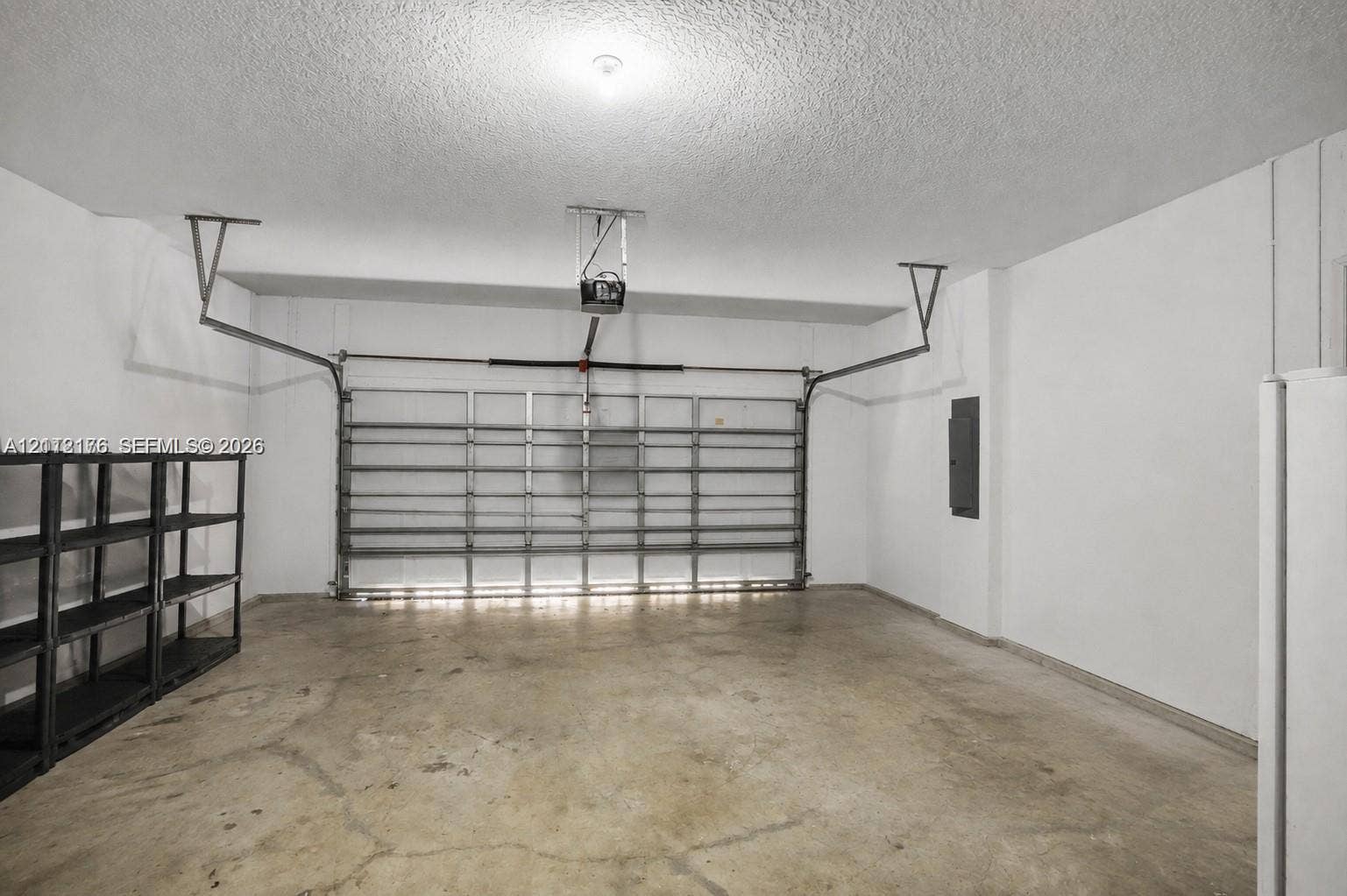 19143 Crystal Street, Weston, FL 33332 Enclosed garage featuring a concrete floor, automated door system, ceiling-mounted opener, and white walls