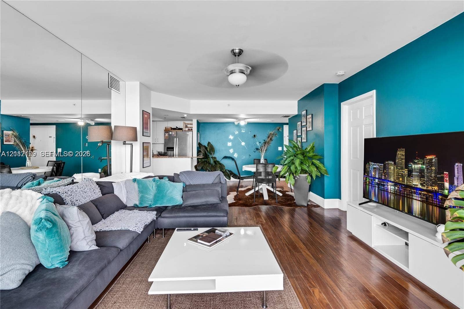 800 Claughton Island Drive, #1604, Miami, Miami, FL 33131 Open living area featuring wood-finish flooring, a wall-to-wall mirrored accent, ceiling fan with integrated lighting, and white built-in media cabinetry