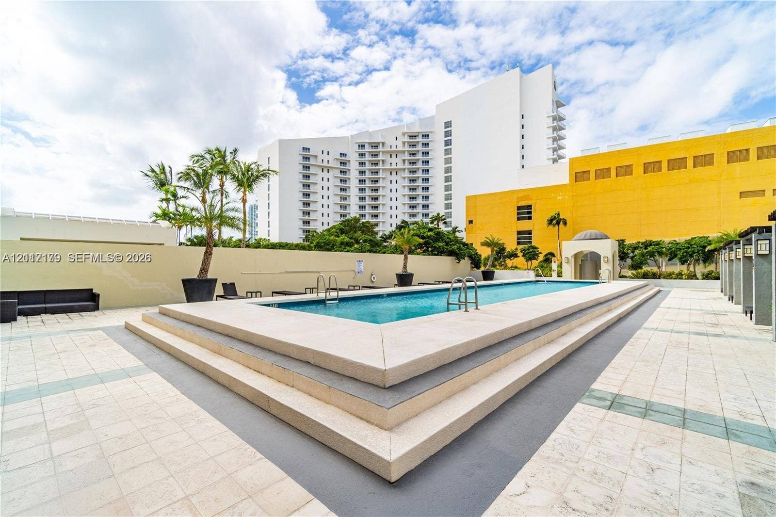 800 Claughton Island Drive, #1604, Miami, Miami, FL 33131 Elevated rectangular swimming pool featuring tiered concrete steps, perimeter coping, and metal entry ladders, set within a tiled deck