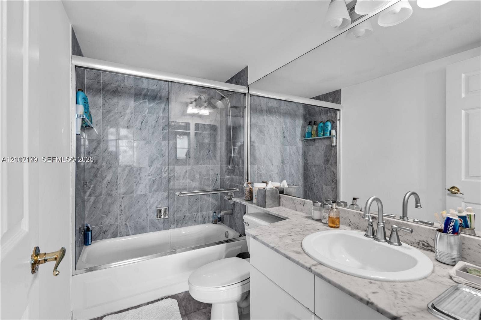800 Claughton Island Drive, #1604, Miami, Miami, FL 33131 Full-width vanity with stone countertop and undermount sink, shower-tub combination with glass enclosure, and floor-to-ceiling stone tile surround