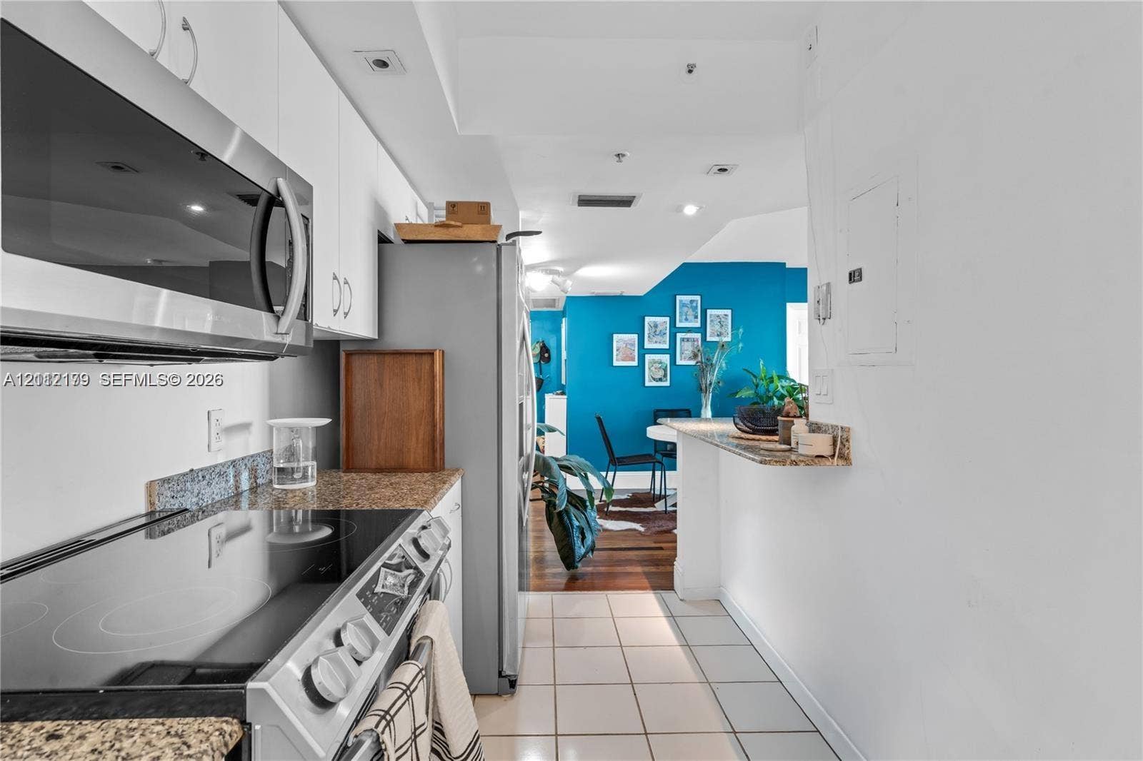 800 Claughton Island Drive, #1604, Miami, Miami, FL 33131 Kitchen featuring white cabinetry, stone-finish countertops, stainless steel appliances, and a breakfast bar