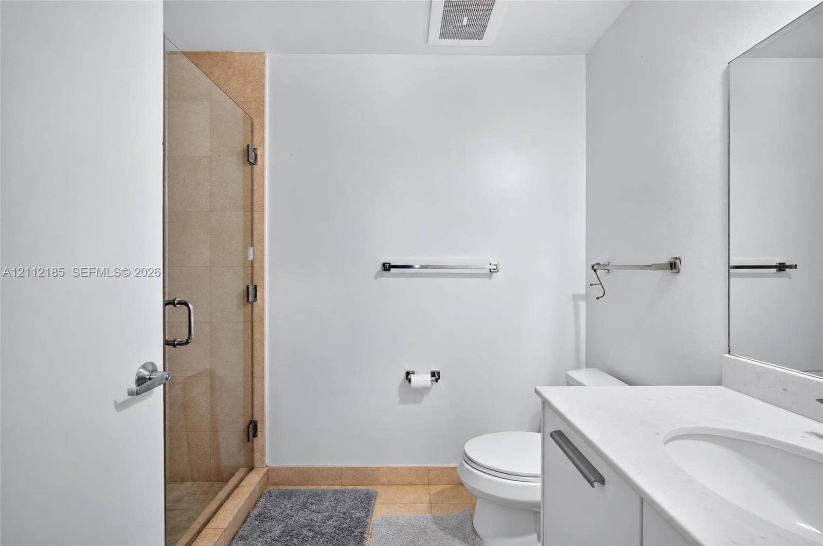 1060 Brickell Avenue, #2401, Miami, FL 33131 Bathroom featuring a frameless glass-enclosed shower with tile surround, a white vanity with a composite countertop, an undermount sink, and a wall-mounted mirror