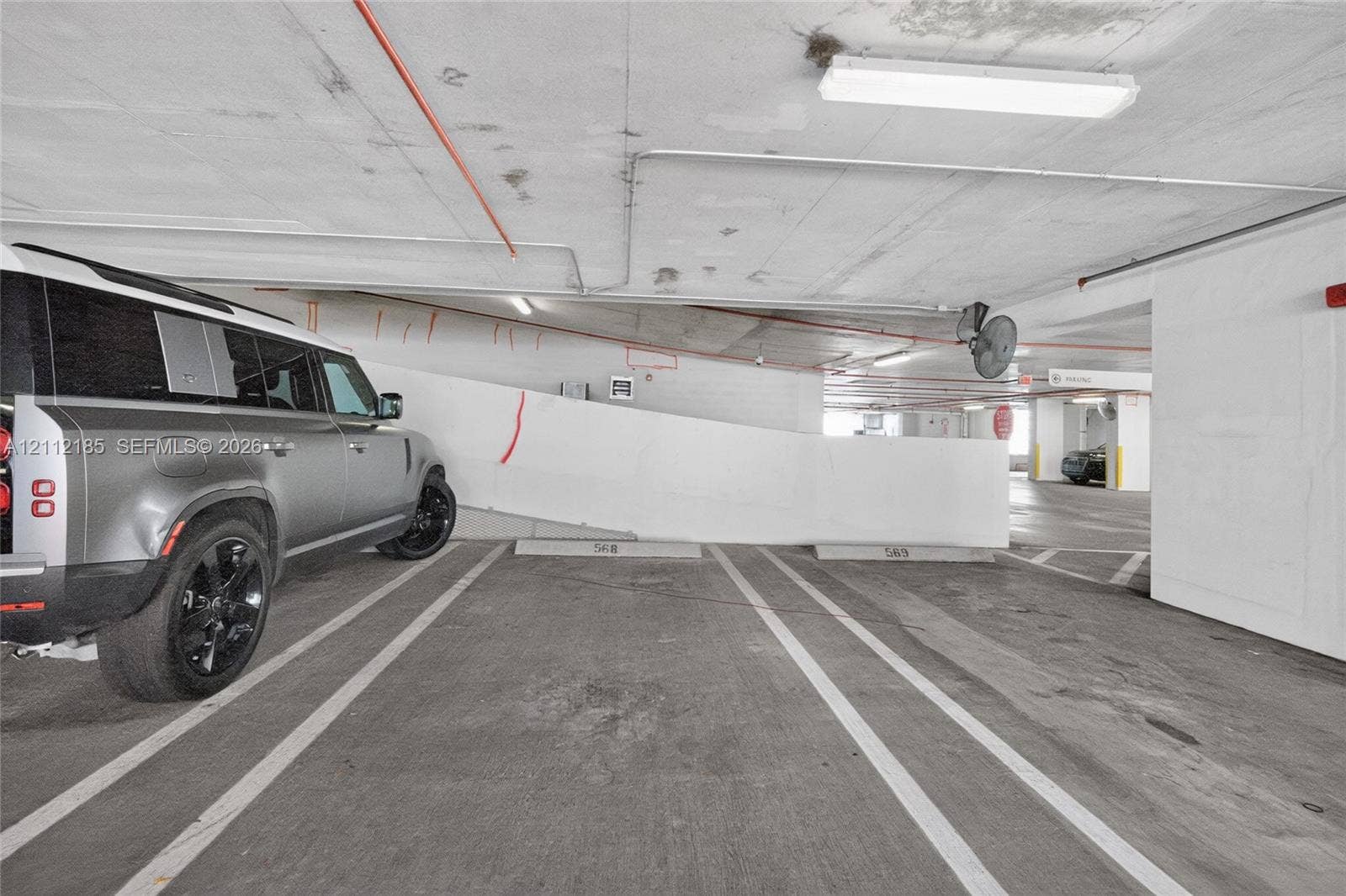 1060 Brickell Avenue, #2401, Miami, FL 33131 Covered parking facility with concrete flooring, designated stalls, and overhead industrial lighting