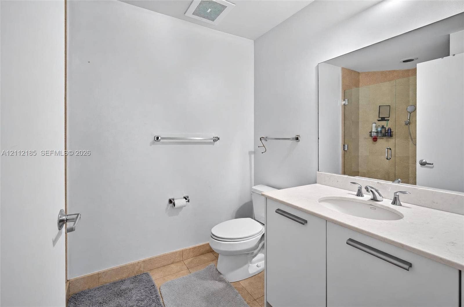 1060 Brickell Avenue, #2401, Miami, FL 33131 Bathroom featuring a white vanity with a stone countertop and undermount sink, large wall-mounted mirror, and a glass-enclosed shower with stone tile surround