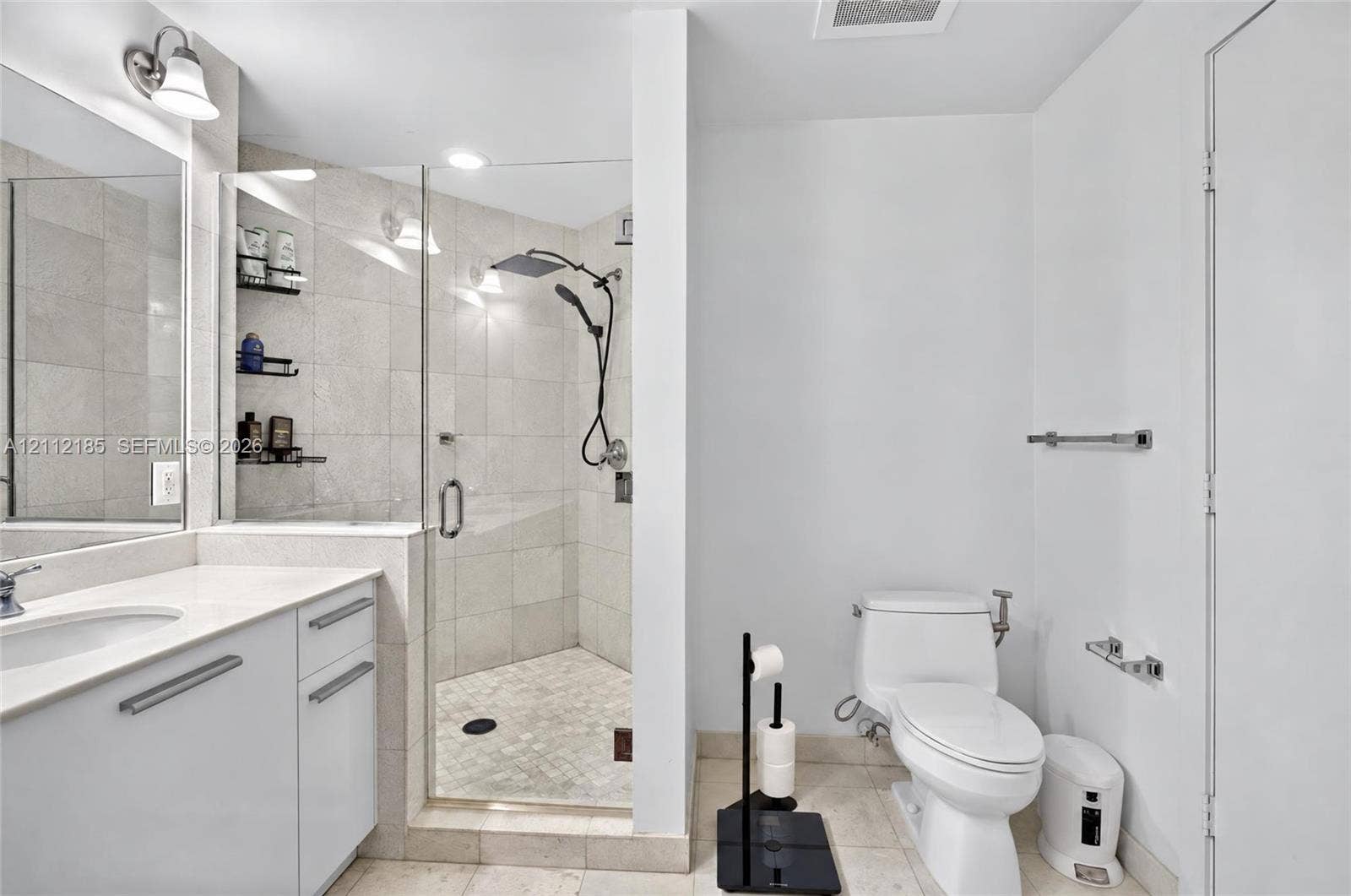 1060 Brickell Avenue, #2401, Miami, FL 33131 Bathroom featuring a white vanity with a composite countertop, an integrated sink, a glass-enclosed shower with tile surround, a rainfall showerhead, and recessed lighting