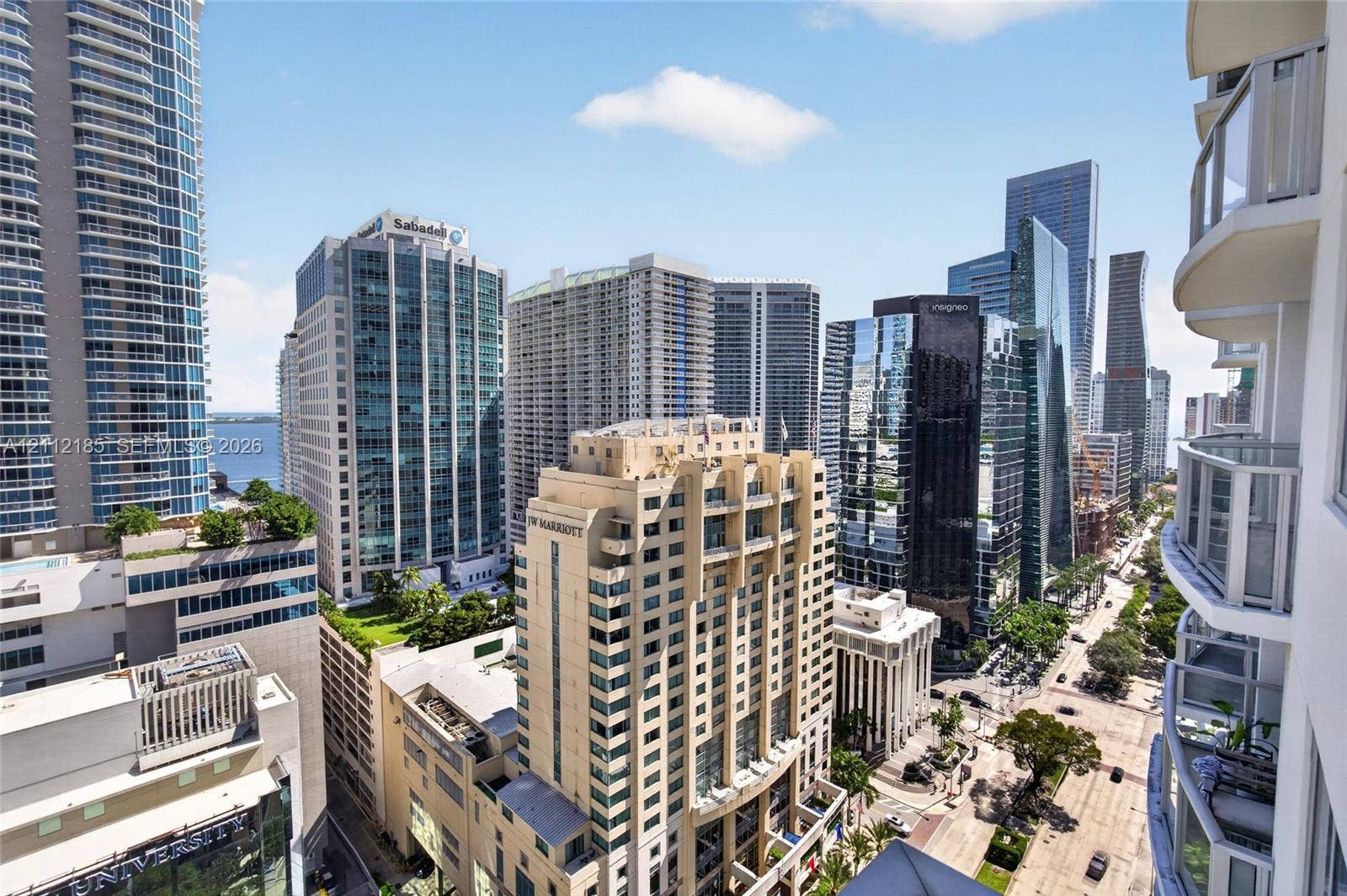 1060 Brickell Avenue, #2401, Miami, FL 33131 High-rise balcony with glass railings overlooking a dense urban cityscape featuring multiple skyscraper structures and street-level thoroughfares