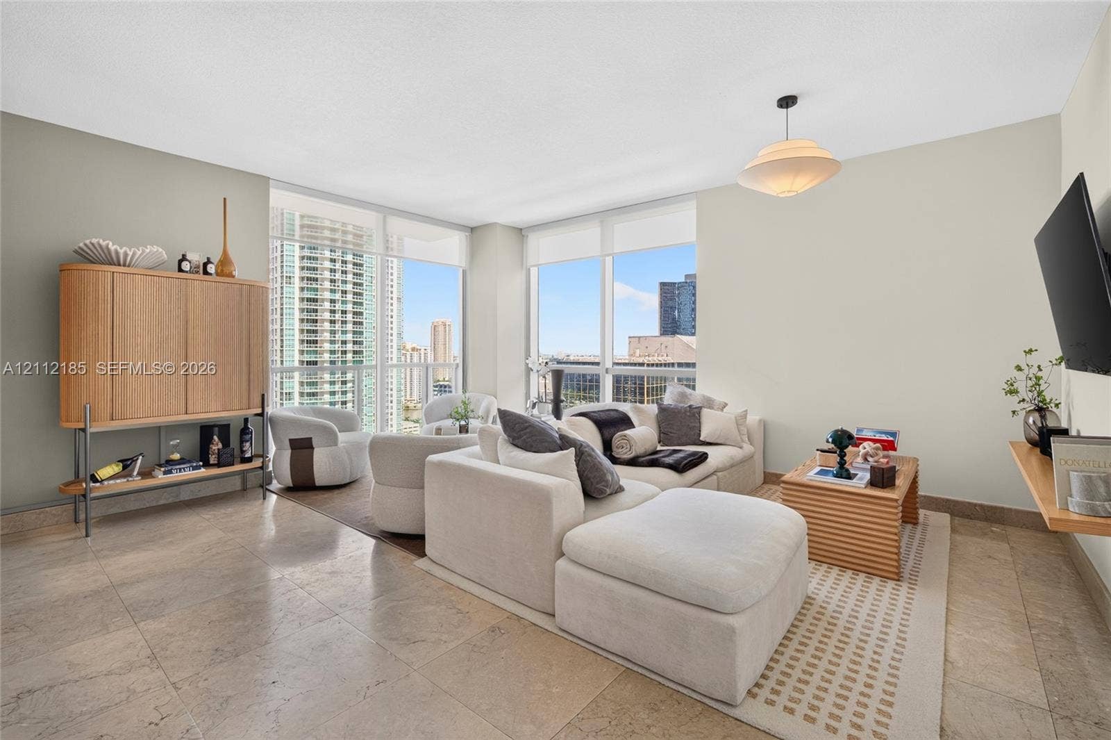 1060 Brickell Avenue, #2401, Miami, FL 33131 Living area featuring floor-to-ceiling windows, natural stone flooring, and a pendant light fixture