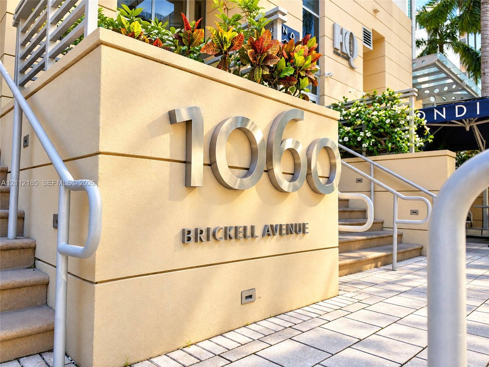 1060 Brickell Avenue, #2401, Miami, FL 33131 Exterior building signage featuring raised metallic house numbers, integrated stucco masonry, paved stone hardscaping, and recessed wall-mounted lighting