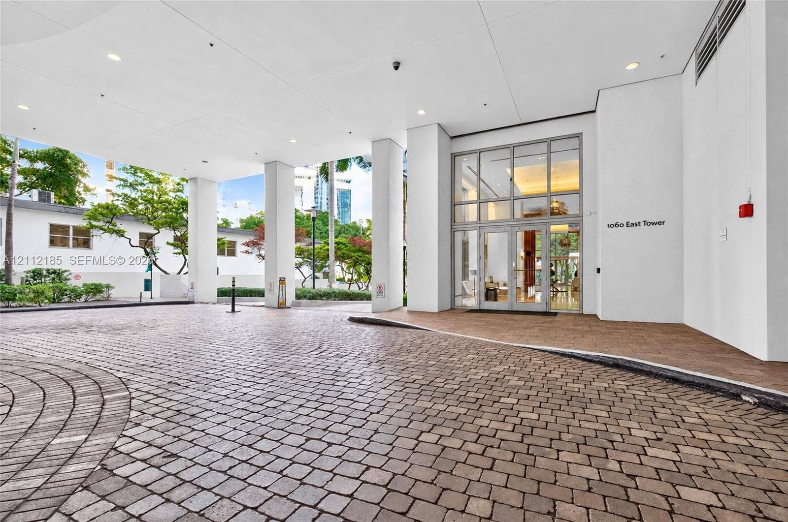 1060 Brickell Avenue, #2401, Miami, FL 33131 Covered motor court entrance featuring stone paver driveway, glass-paneled double entry doors, high ceilings with recessed lighting, and support columns