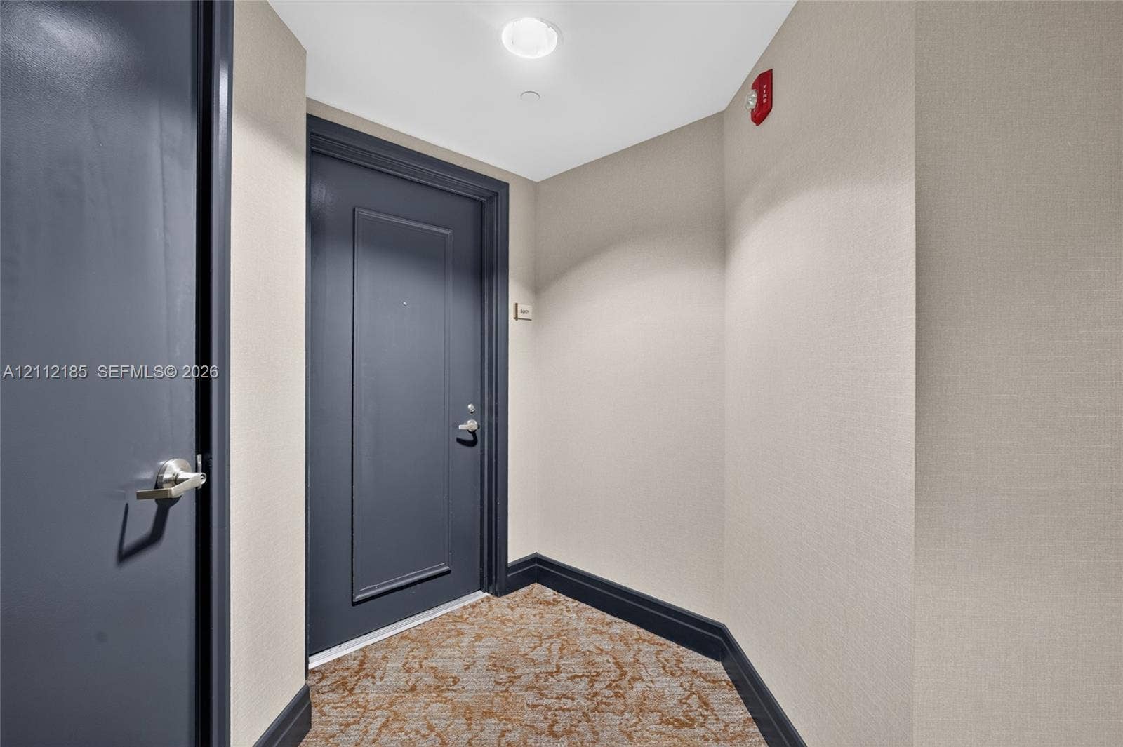 1060 Brickell Avenue, #2401, Miami, FL 33131 Entryway featuring dark-finish paneled doors, neutral textured wall coverings, and patterned carpeting with bold trim detailing
