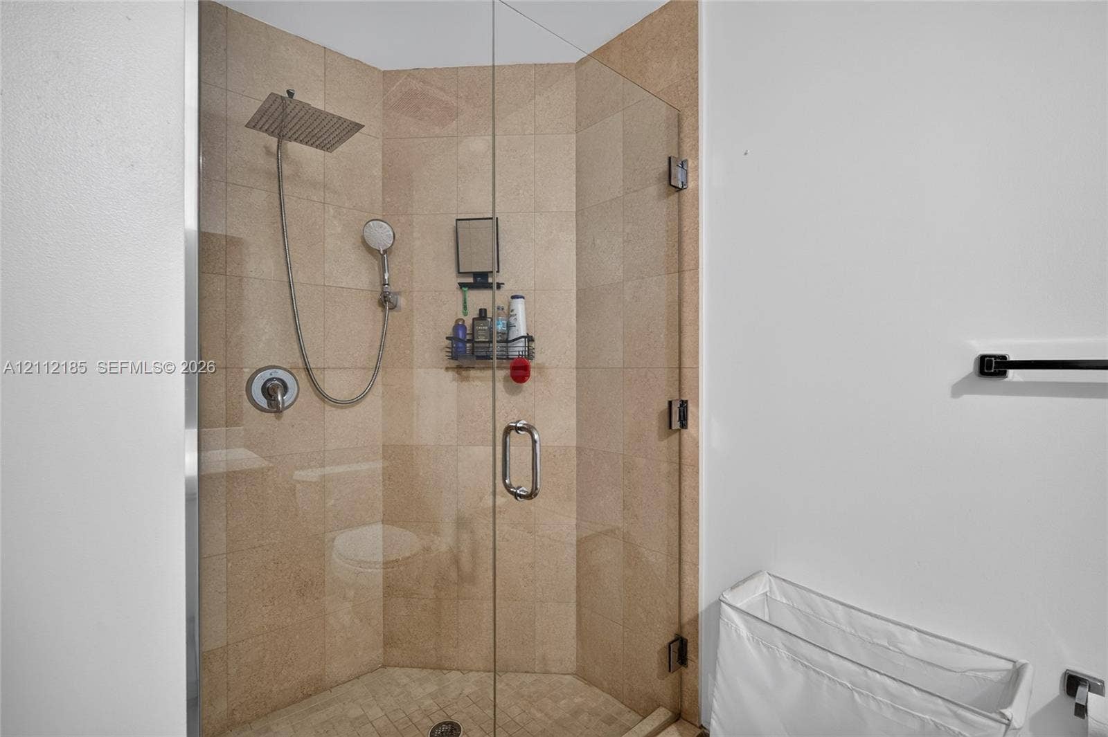 1060 Brickell Avenue, #2401, Miami, FL 33131 Walk-in shower featuring tile walls, a frameless glass enclosure, a square rainfall showerhead, and a handheld shower wand