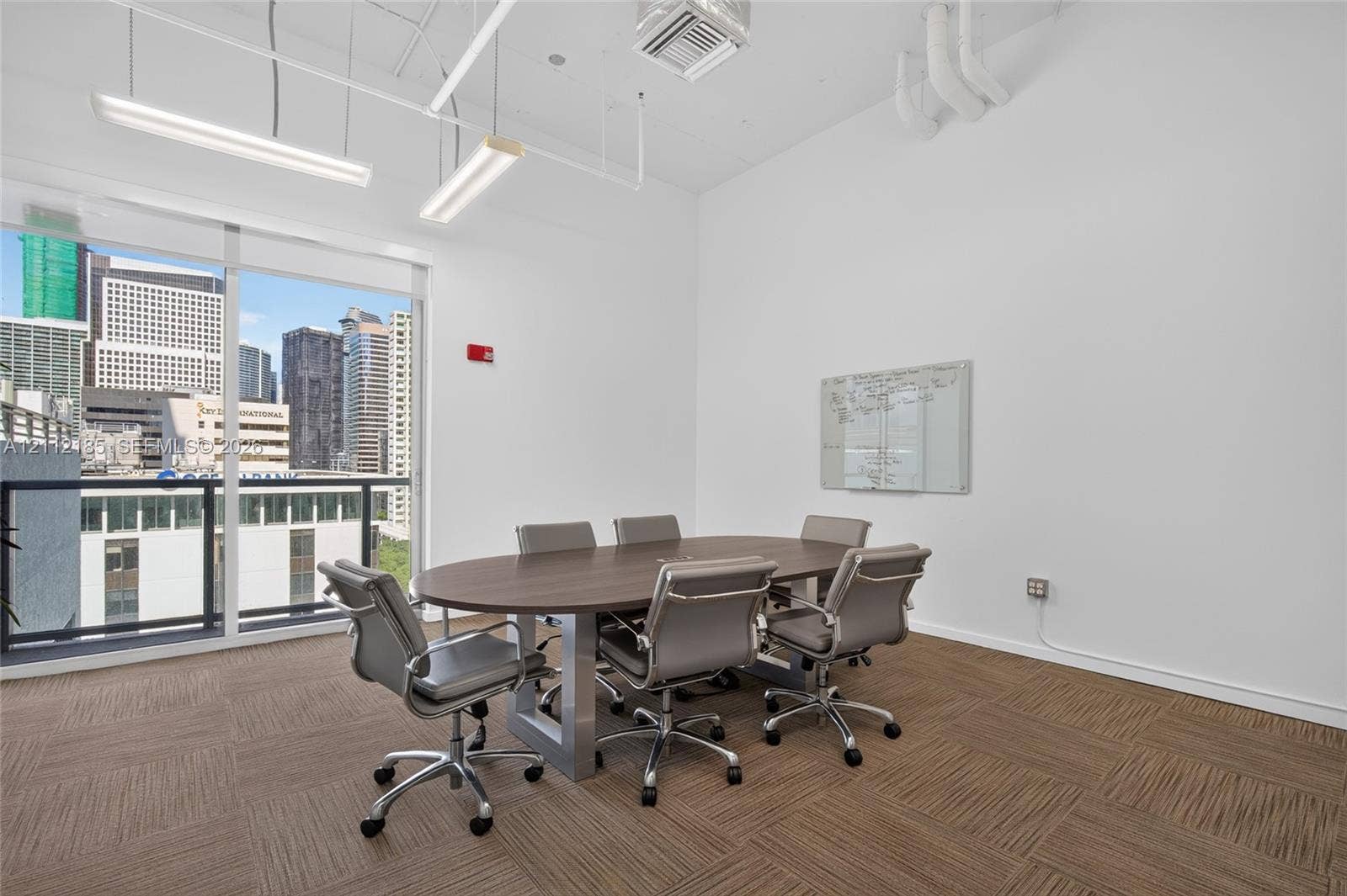 1060 Brickell Avenue, #2401, Miami, FL 33131 Open-concept space featuring floor-to-ceiling windows, urban skyscraper backdrop, high ceilings, linear pendant lighting, and modular carpet tiling