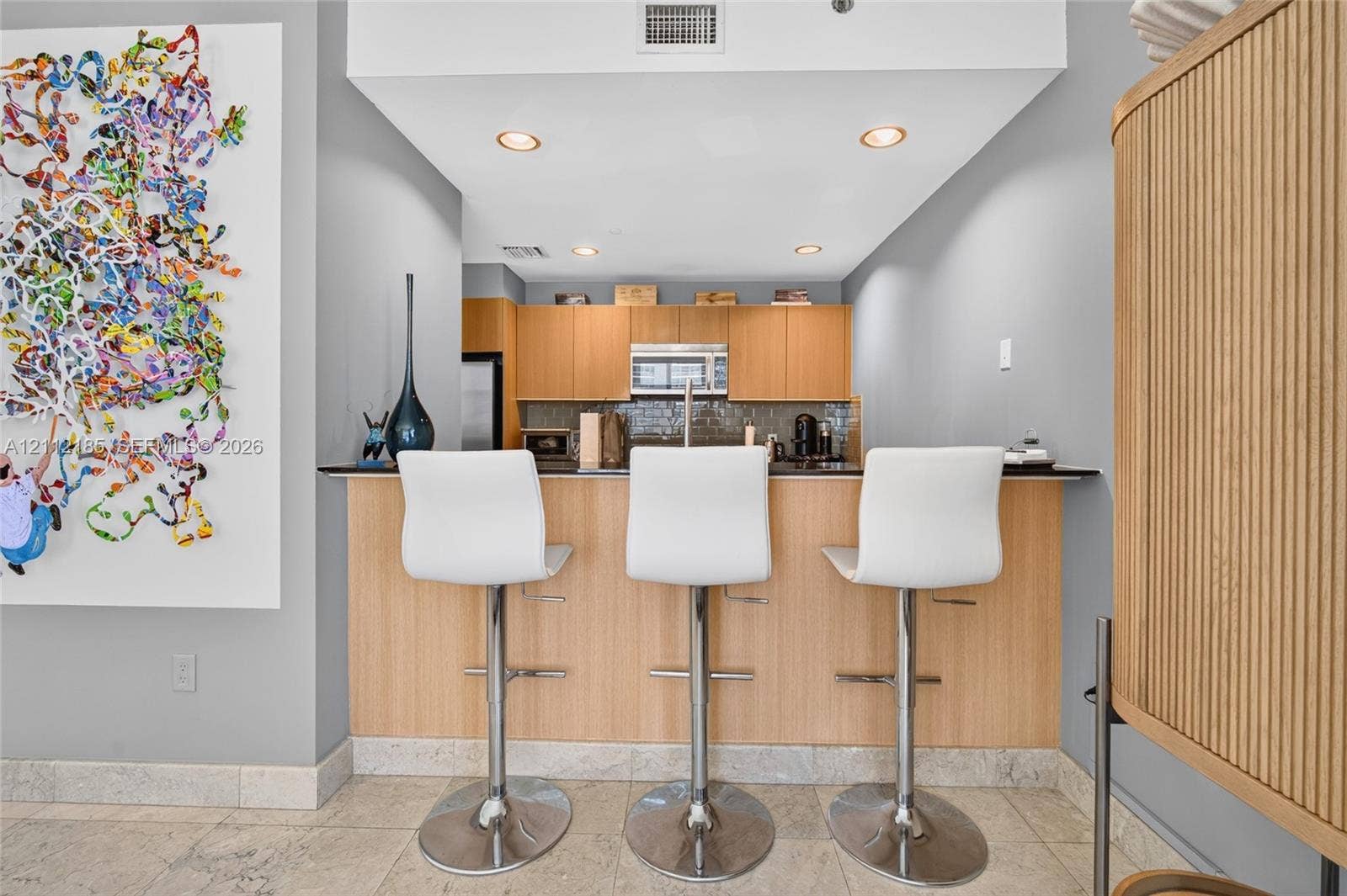 1060 Brickell Avenue, #2401, Miami, FL 33131 Kitchen featuring flat-panel wood cabinetry, dark stone countertops, built-in microwave, recessed ceiling lighting, and tile flooring