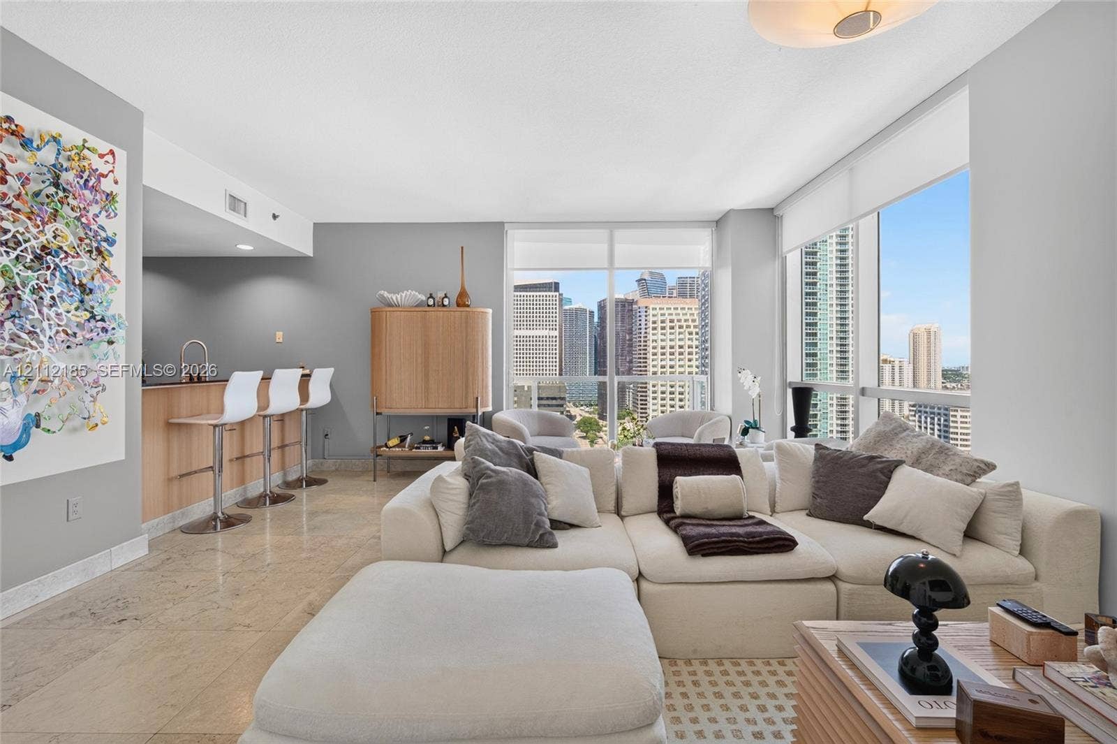 1060 Brickell Avenue, #2401, Miami, FL 33131 Open-concept living area featuring stone flooring, floor-to-ceiling windows, and a built-in kitchen island with a sink and faucet