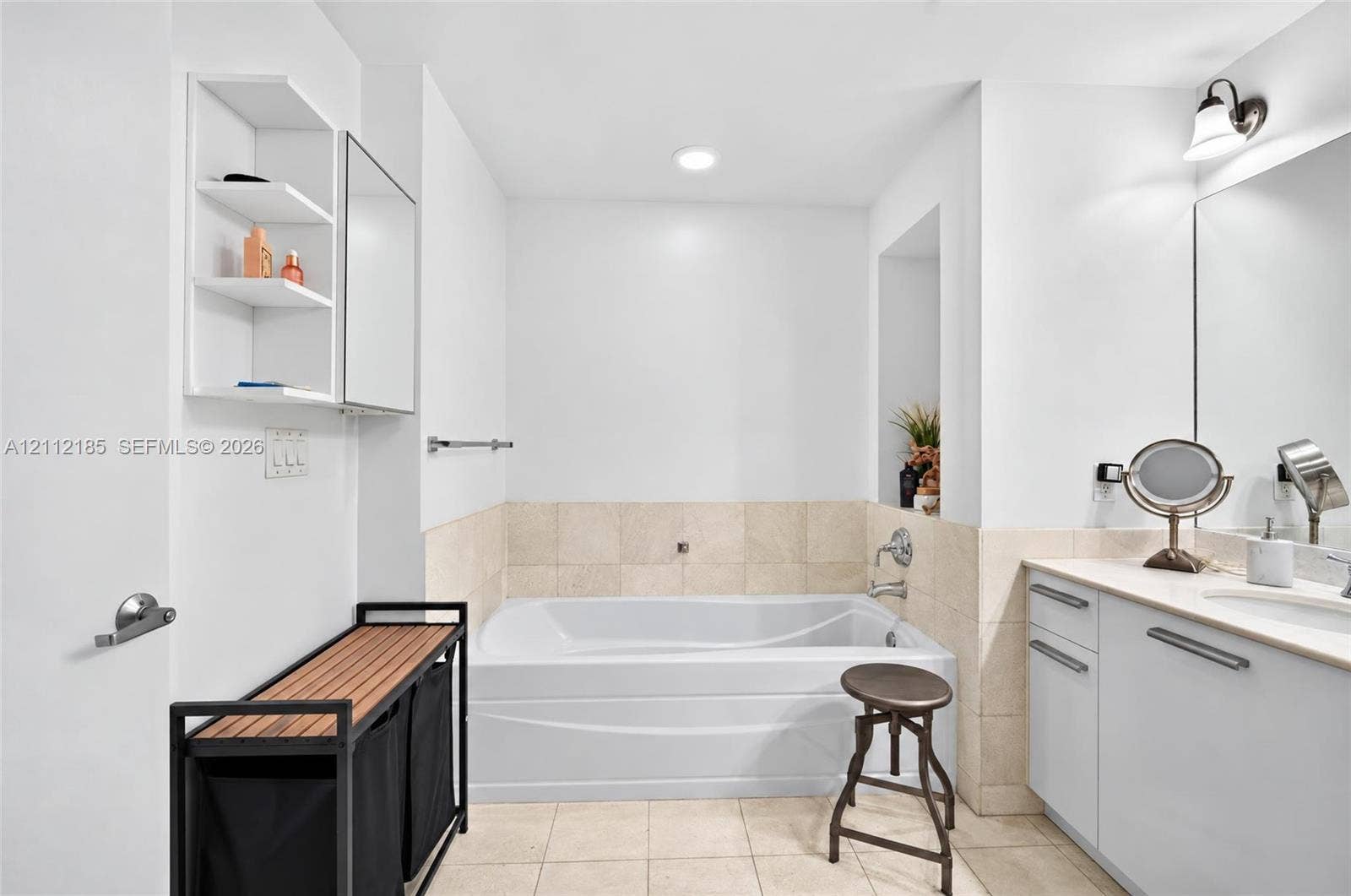 1060 Brickell Avenue, #2401, Miami, FL 33131 Bathroom featuring a deep soaking tub with neutral tile surround, built-in shelving, vanity with integrated basin, and polished chrome hardware