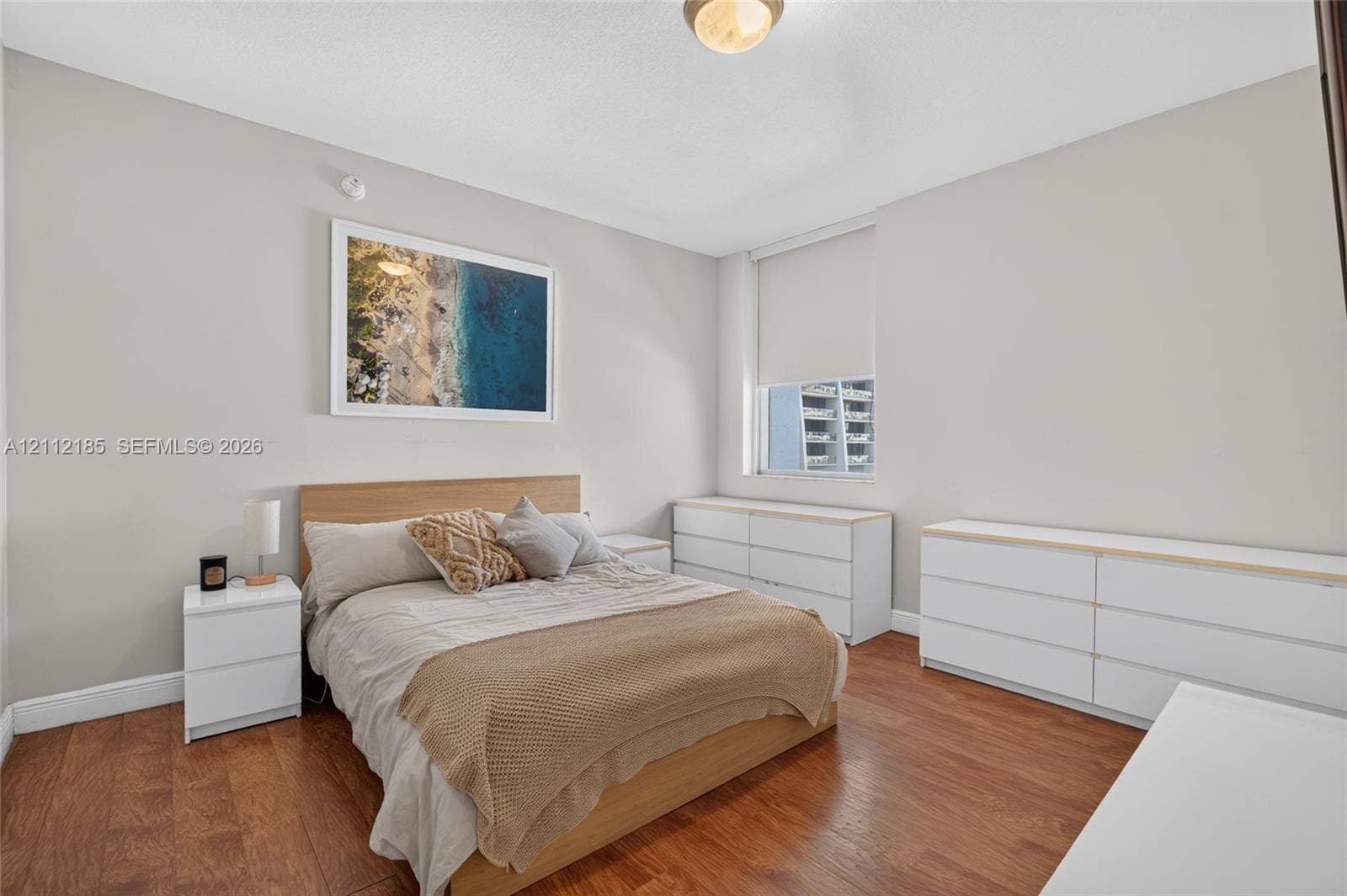 1060 Brickell Avenue, #2401, Miami, FL 33131 Room interior featuring wood-finish flooring, neutral wall tones, and a window with a roller shade
