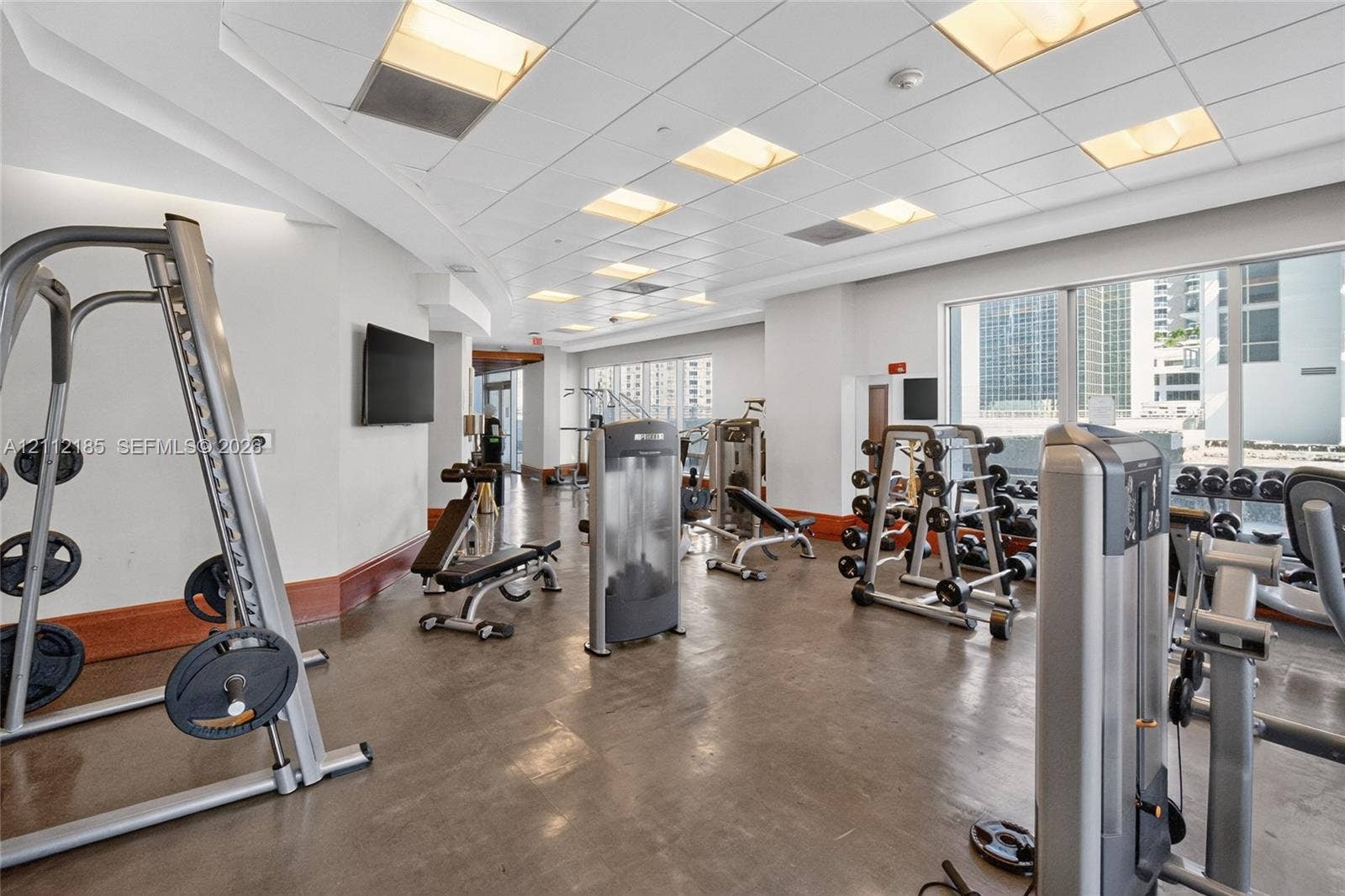 1060 Brickell Avenue, #2401, Miami, FL 33131 Fitness facility featuring a polished concrete floor, drop ceiling with recessed lighting, large floor-to-ceiling windows, and wood-tone wall trim