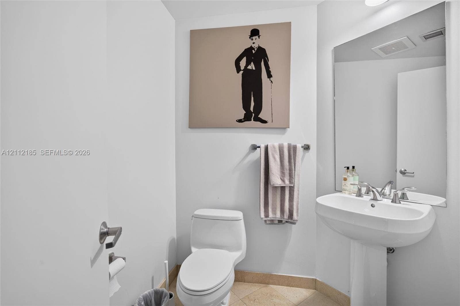 1060 Brickell Avenue, #2401, Miami, FL 33131 Powder room featuring a pedestal sink, dual-handle chrome faucet, large wall-mounted mirror, and tile flooring