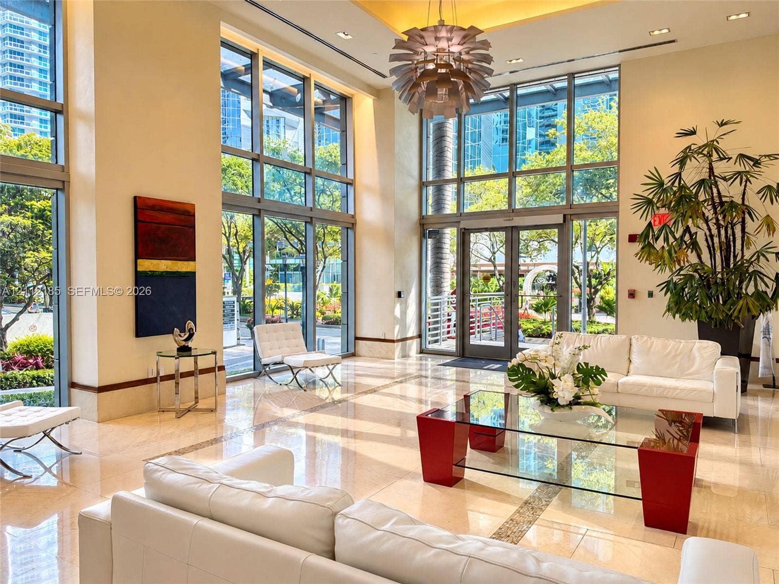 1060 Brickell Avenue, #2401, Miami, FL 33131 Double-height lobby featuring floor-to-ceiling glass windows, recessed ceiling lighting, polished stone flooring, and a decorative modern pendant chandelier