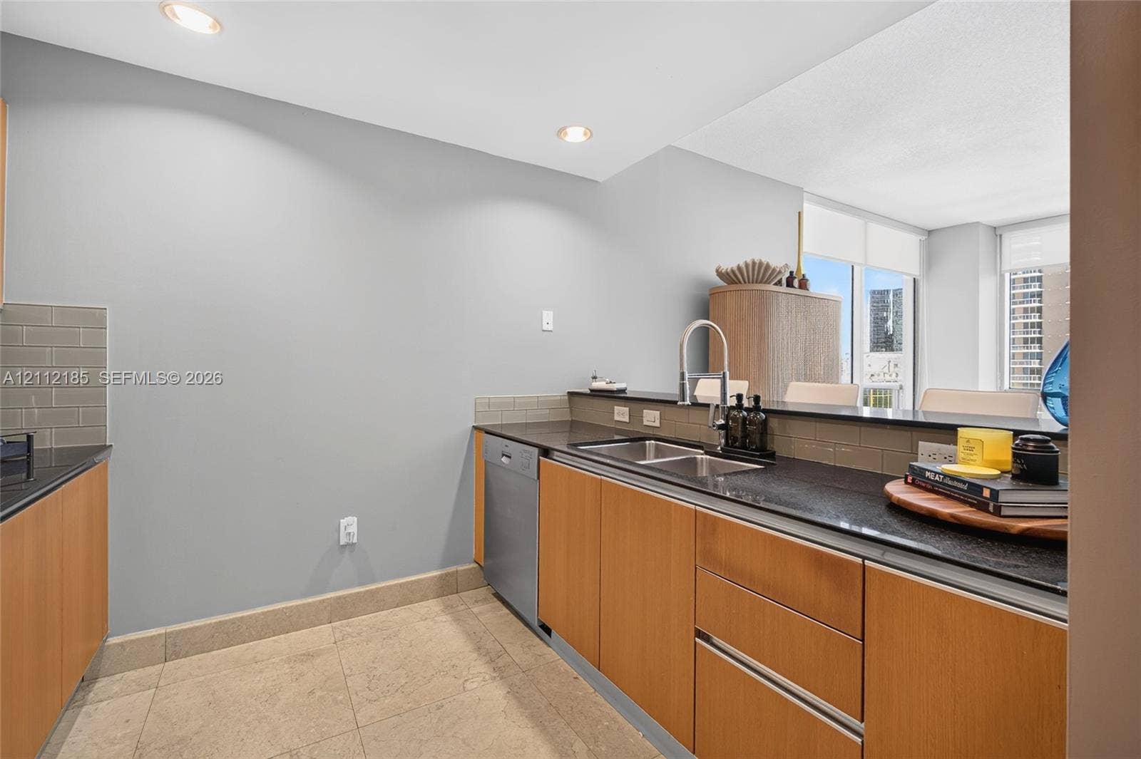 1060 Brickell Avenue, #2401, Miami, FL 33131 Kitchen featuring flat-panel wood cabinetry, dark stone countertops, an undermount double-basin sink with a high-arch faucet, integrated dishwasher, and tile backsplash