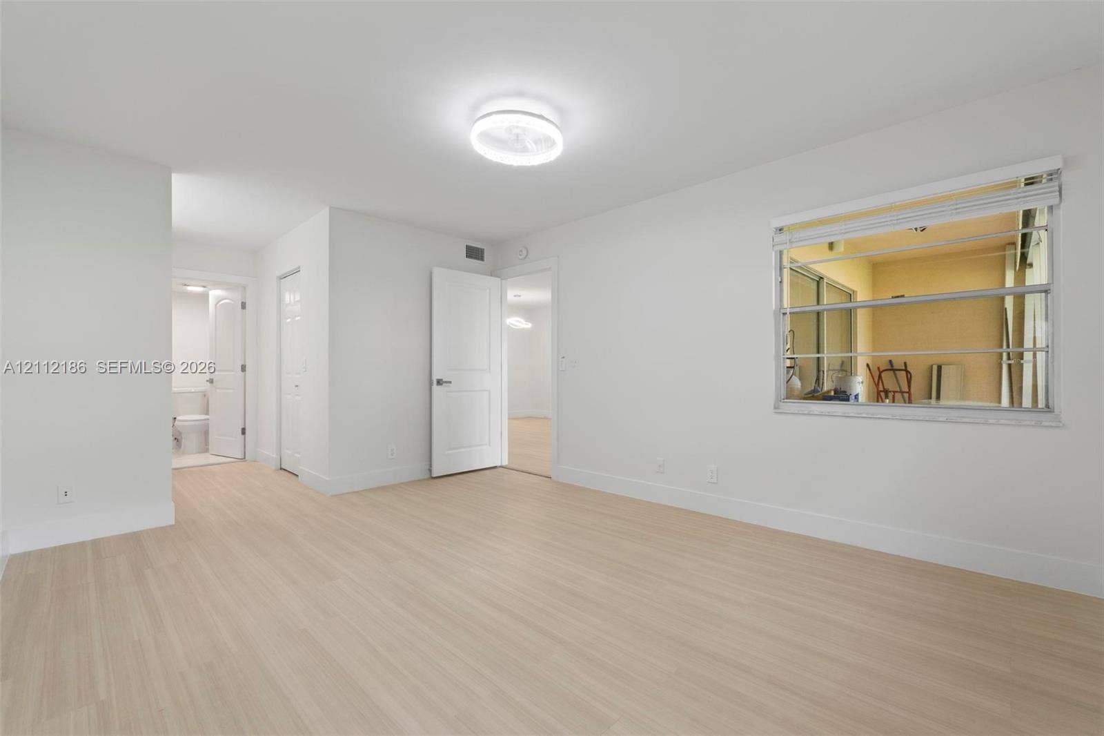 1300 SW 124th Terrace, #107P, Pembroke Pines, Pembroke Pines, FL 33027 Interior room featuring light wood-finish flooring, neutral wall tones, multi-pane horizontal sliding windows, and a flush-mount ceiling light fixture