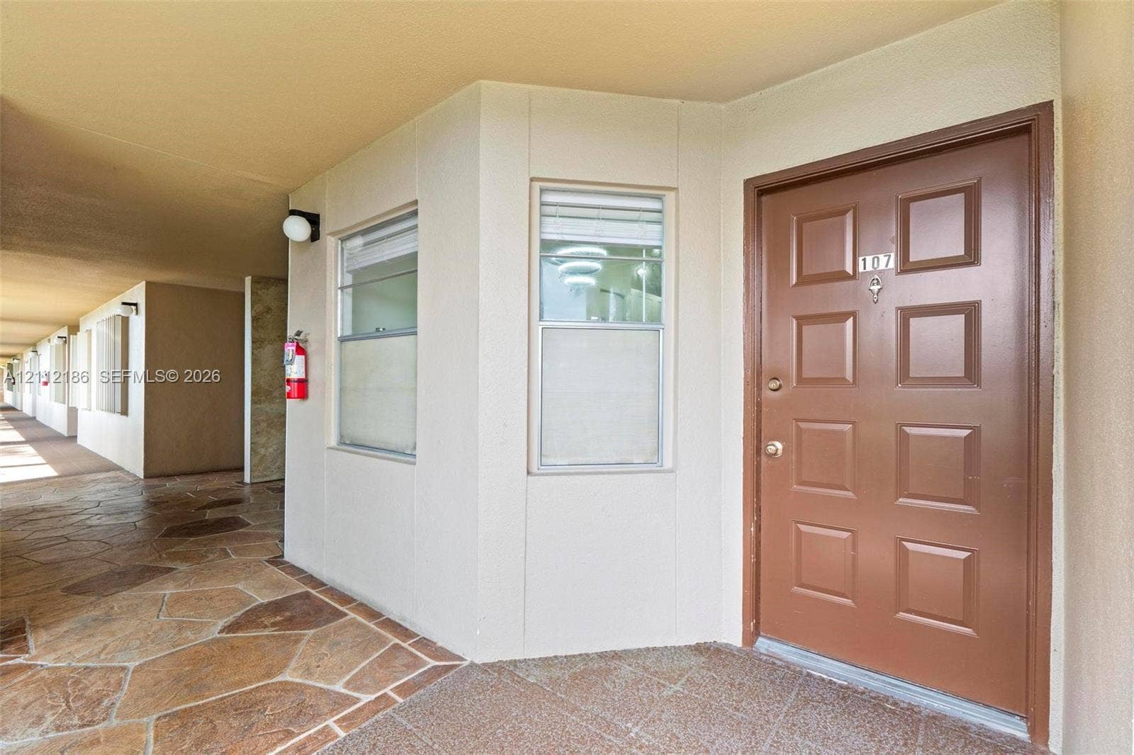 1300 SW 124th Terrace, #107P, Pembroke Pines, Pembroke Pines, FL 33027 Entrance featuring a solid-core raised panel door, stone-finish exterior flooring, and double-hung windows