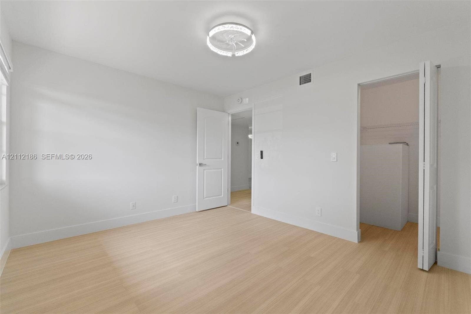 1300 SW 124th Terrace, #107P, Pembroke Pines, Pembroke Pines, FL 33027 Light-toned wood-finish flooring, crisp neutral wall paint, modern ceiling-mounted lighting fixture, and interior doors with integrated closets