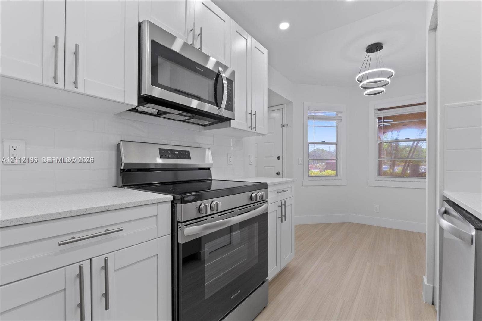 1300 SW 124th Terrace, #107P, Pembroke Pines, Pembroke Pines, FL 33027 Kitchen featuring white shaker-style cabinetry, stainless steel appliances, light-toned stone countertops, subway tile backsplash, and tiered pendant lighting