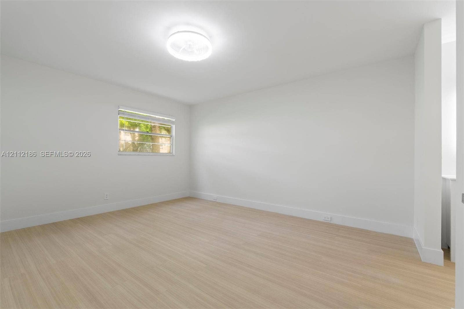 1300 SW 124th Terrace, #107P, Pembroke Pines, Pembroke Pines, FL 33027 Interior room featuring light-toned wood-finish flooring, neutral walls, a single-pane window, and a flush-mount circular ceiling fixture